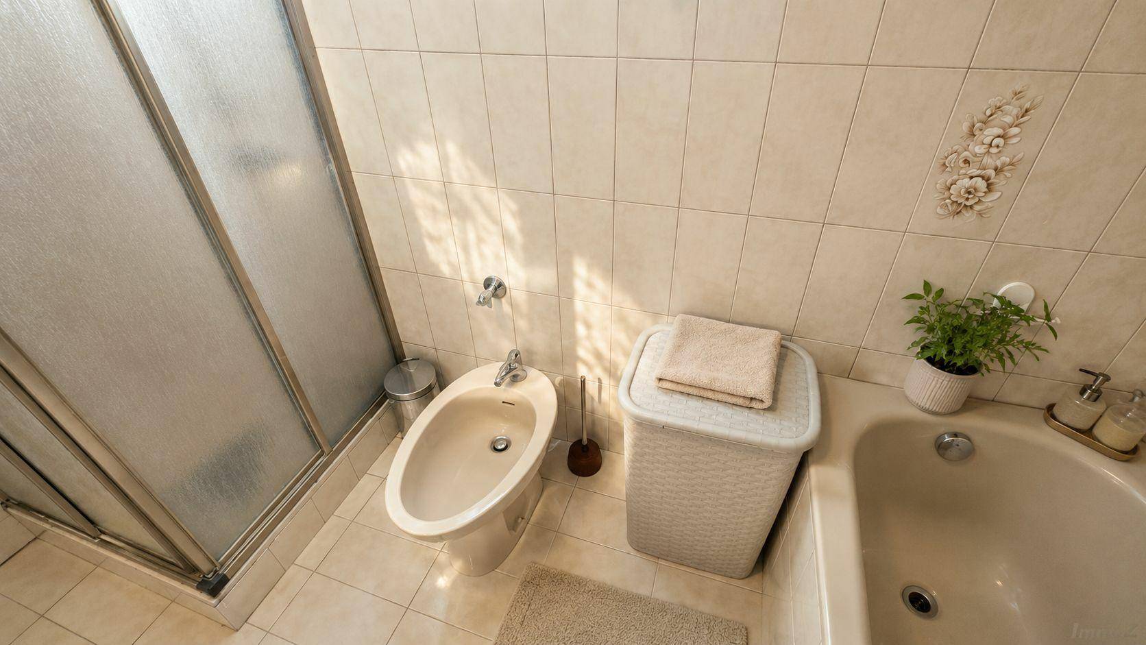Helles Badezimmer mit Badewanne, Bidet und Duschkabine, komplett gefliest.