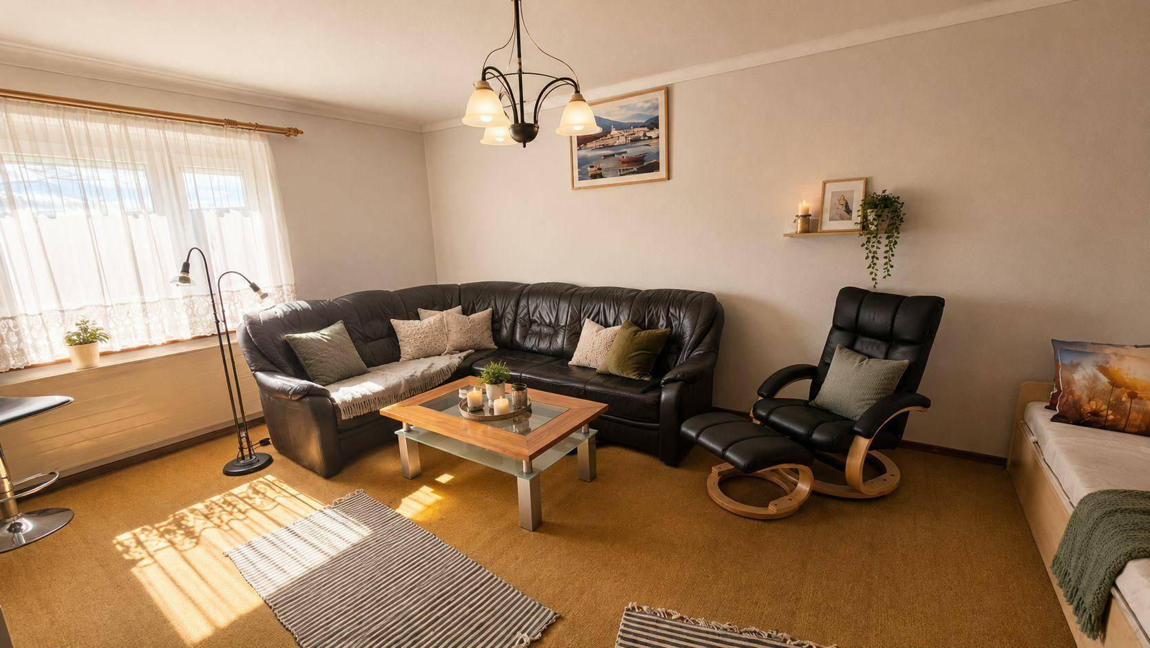 Helles Wohnzimmer mit dunklem Ledersofa, gemütlichem Sessel und Teppichboden, durchflutet von natürlichem Licht.