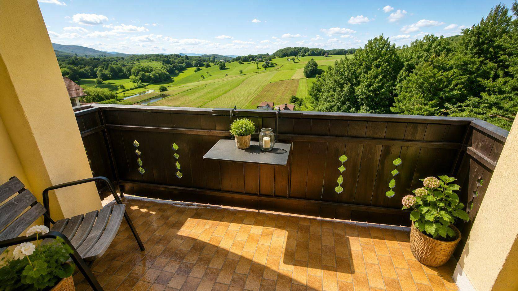 Gemütlicher Balkon mit Fliesenboden und weitem Blick über die grüne Landschaft.