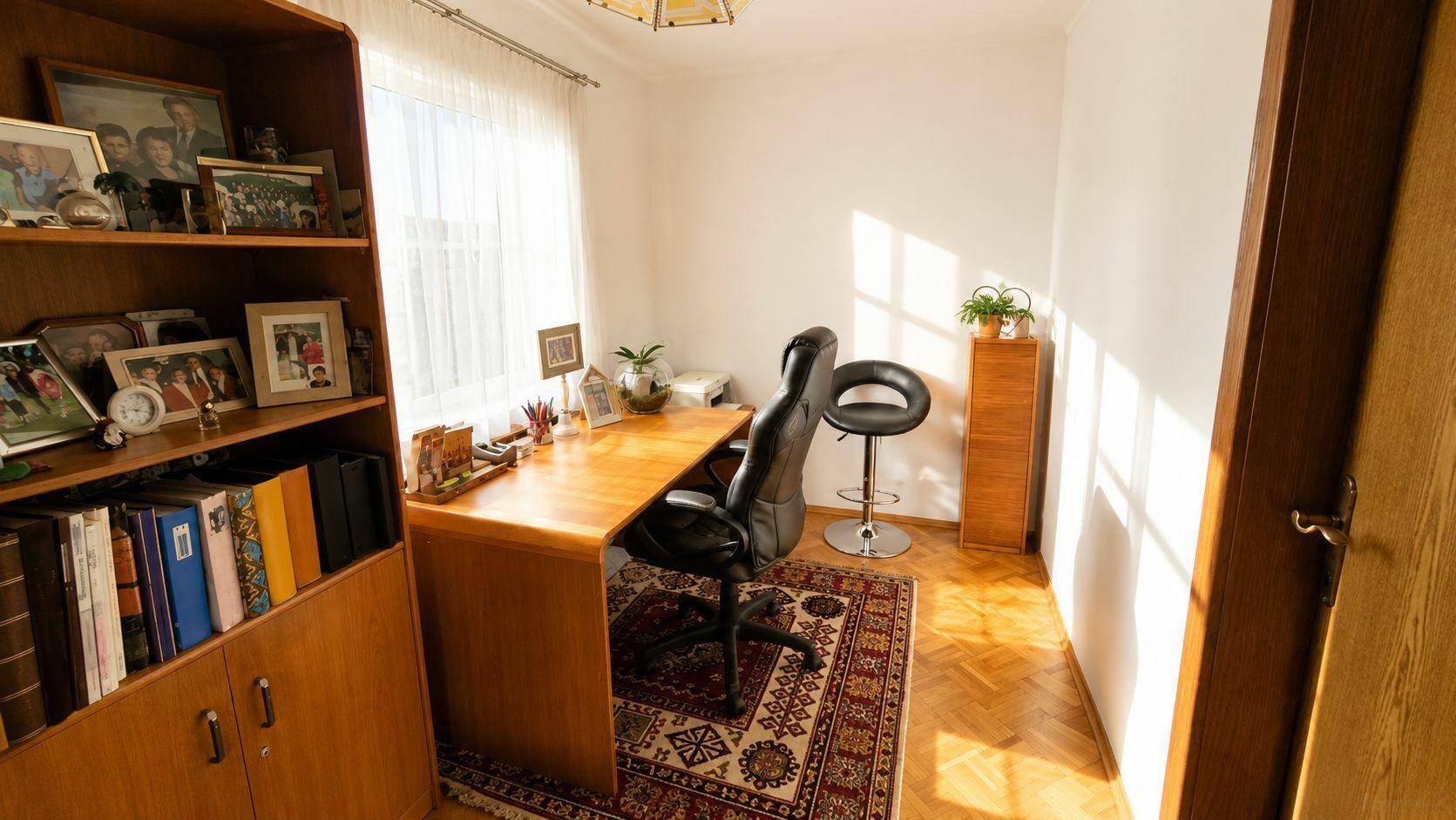 Funktionales Arbeitszimmer mit Holzschreibtisch, Bücherregal und Teppichboden.