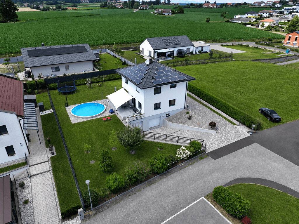 Weitläufige Luftaufnahme des Hauses mit großem Garten, Pool und Photovoltaik auf dem Dach.