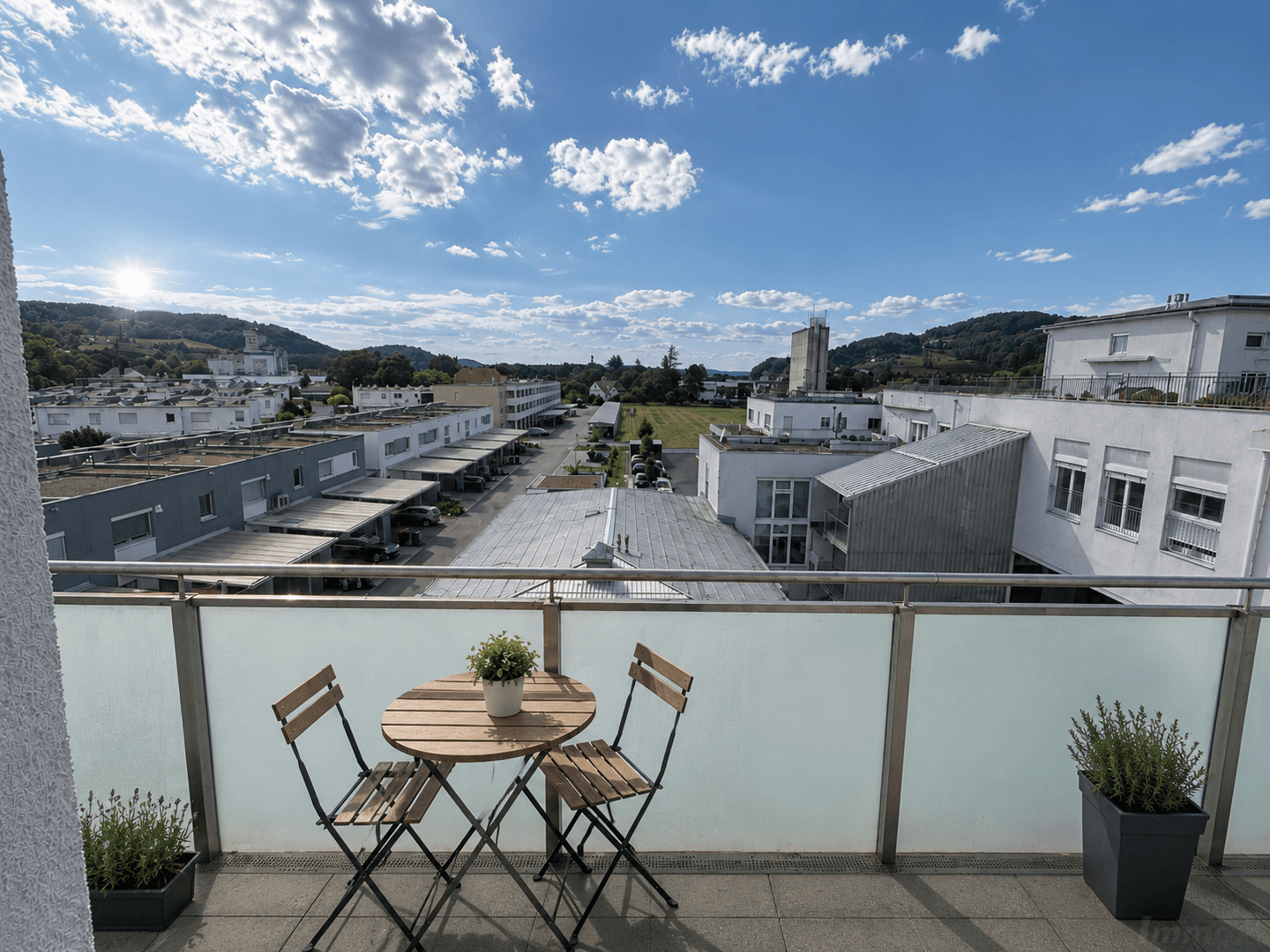 Sonniger Balkon mit Sitzgelegenheiten und weitem Blick über die Stadt und die Umgebung.