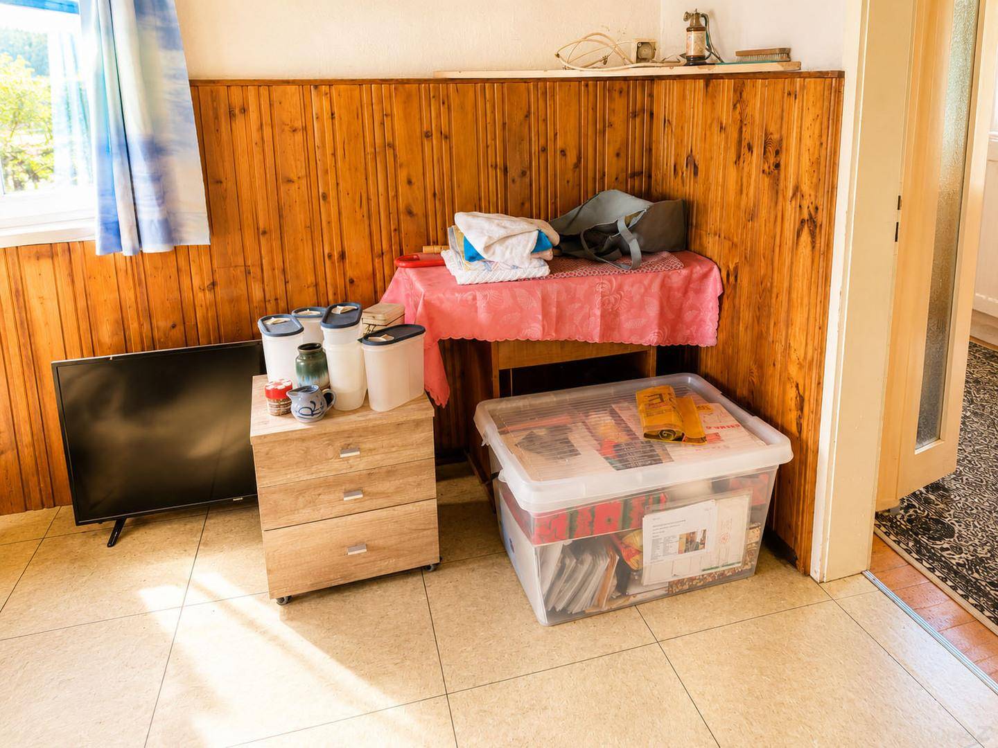 Praktischer Raum mit Holzvertäfelung und Fliesenboden, genutzt als Abstell- oder Arbeitsbereich.