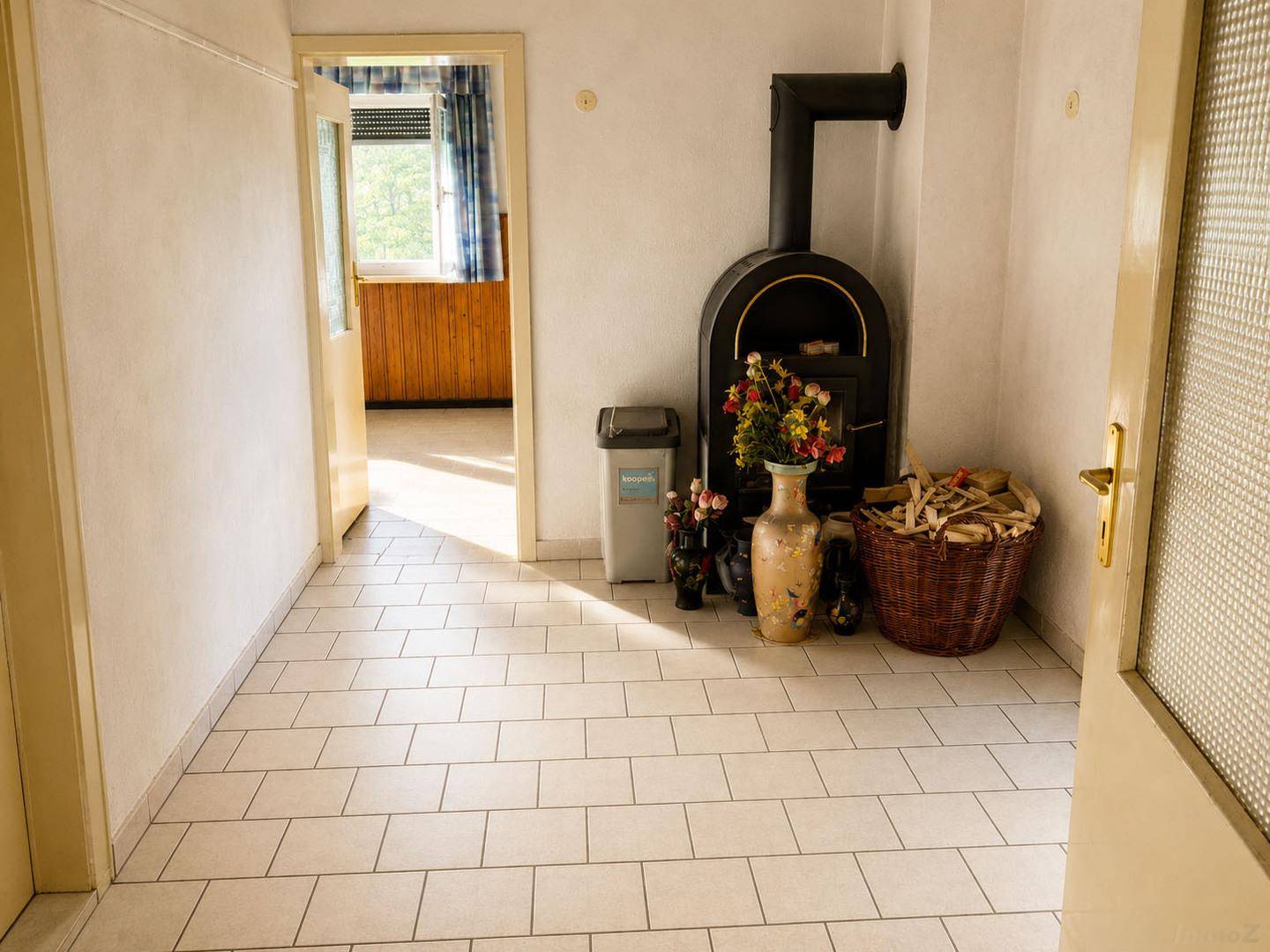 Heller Flur mit Fliesenboden und einem traditionellen Holzofen als zentrale Wärmequelle.
