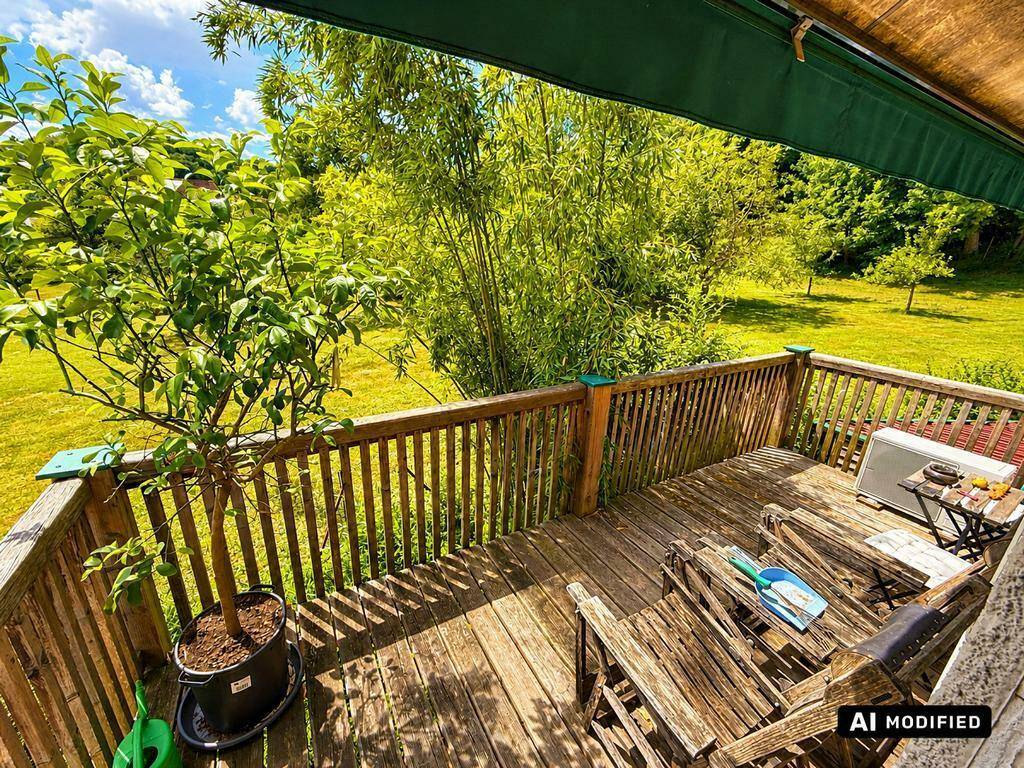 Holzterrasse mit Gartenmöbeln und weitem Blick ins Grüne.
