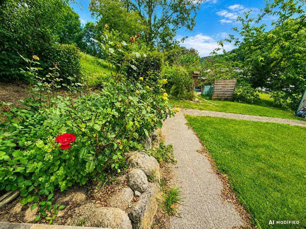 Gartenweg umgeben von blühenden Rosenbüschen und Natursteinen in einer grünen Umgebung.