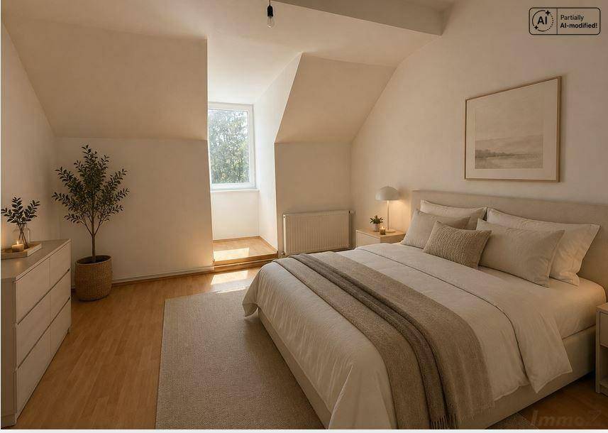 Gemütliches Schlafzimmer im Dachgeschoss mit Holzboden, schrägen Wänden und viel Tageslicht.
