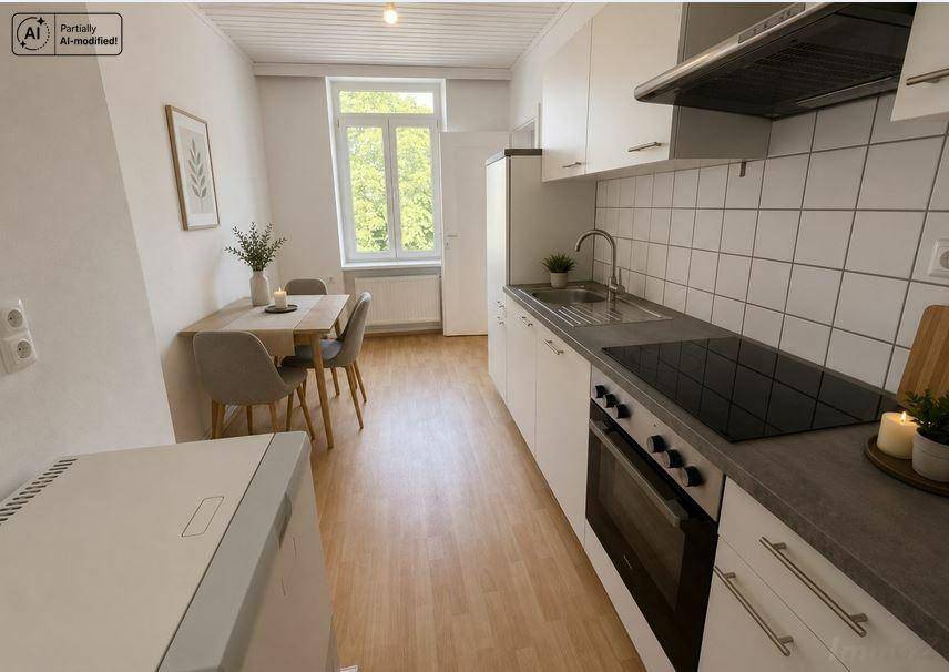 Funktionale Küche mit weißen Schränken, Induktionskochfeld und Essbereich am Fenster.
