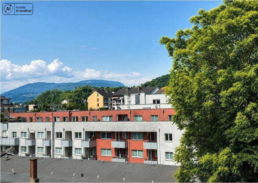 Blick auf Wohngebäude mit farbigen Fassaden und grünen Bäumen im Vordergrund.