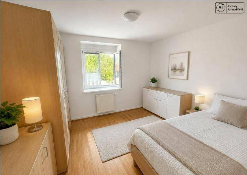 Helles Schlafzimmer mit Holzboden, großem Fenster und schlichten Holzmöbeln.