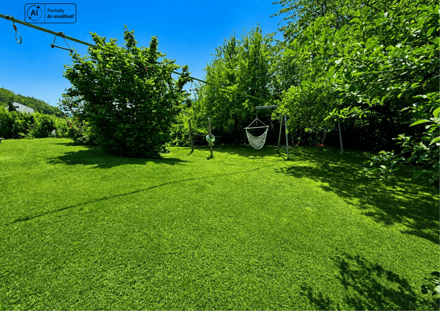 Große, gepflegte Rasenfläche im Garten mit Spielgeräten und üppiger Bepflanzung.