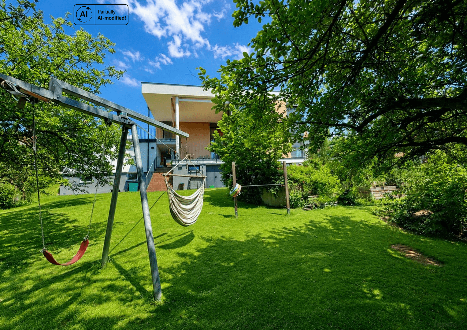 Großer grüner Garten mit Schaukel und Hängematte vor dem modernen Wohnhaus.
