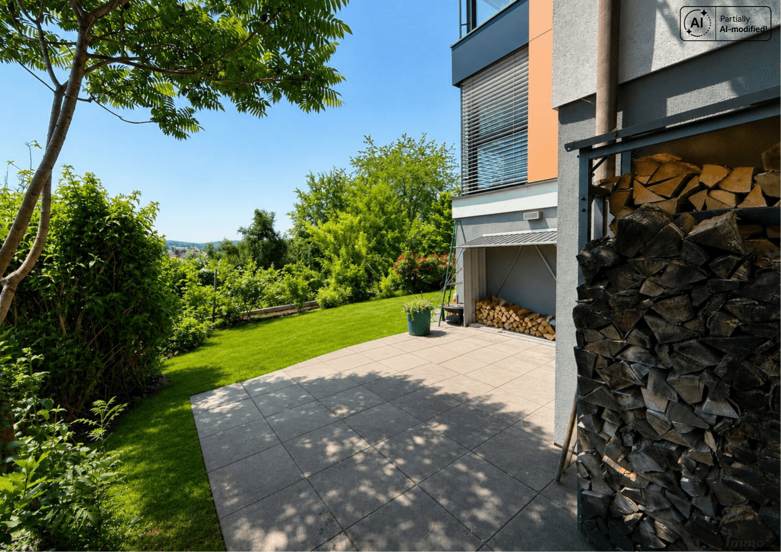 Gepflegter Gartenbereich mit gepflasterter Terrasse und Holzstapel für den Kamin.