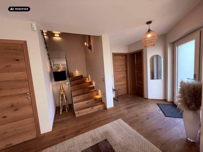 Einladender Eingangsbereich mit Holzboden, moderner Treppe und stilvoller Beleuchtung.