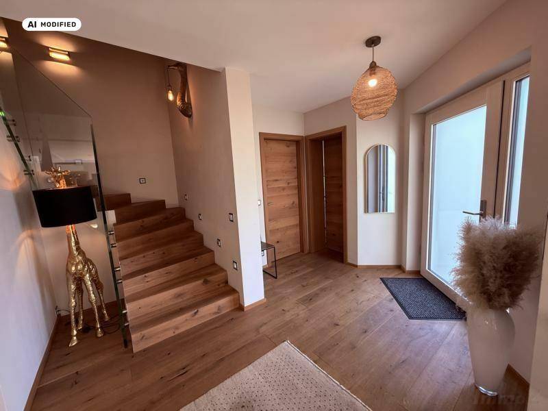 Geräumiger Eingangsbereich mit Holzboden, moderner Treppe und indirekter Beleuchtung.