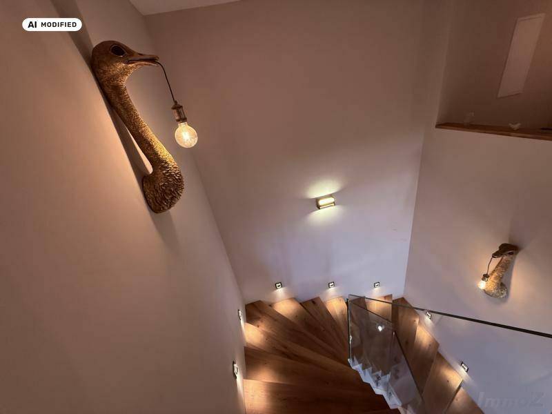 Geschwungene Holztreppe mit Glasgeländer und dekorativer Wandbeleuchtung.