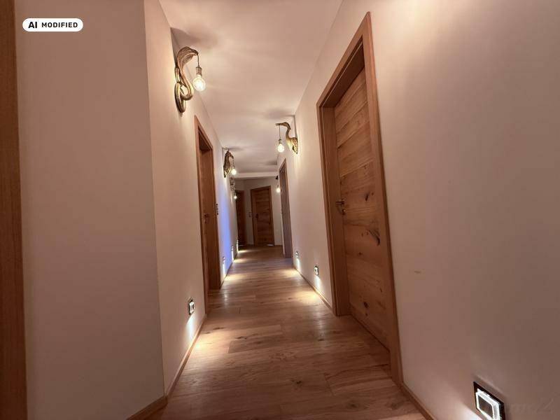 Heller Flur mit Holzboden, mehreren Holztüren und indirekter Beleuchtung.