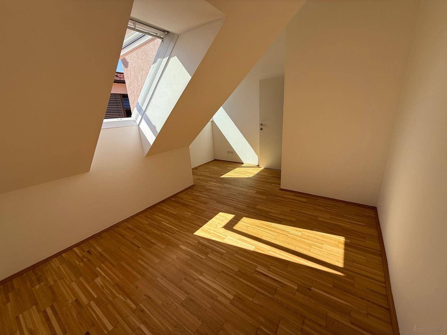 Heller Raum im Dachgeschoss mit Parkettboden und Dachfenster, ideal als Arbeitszimmer.