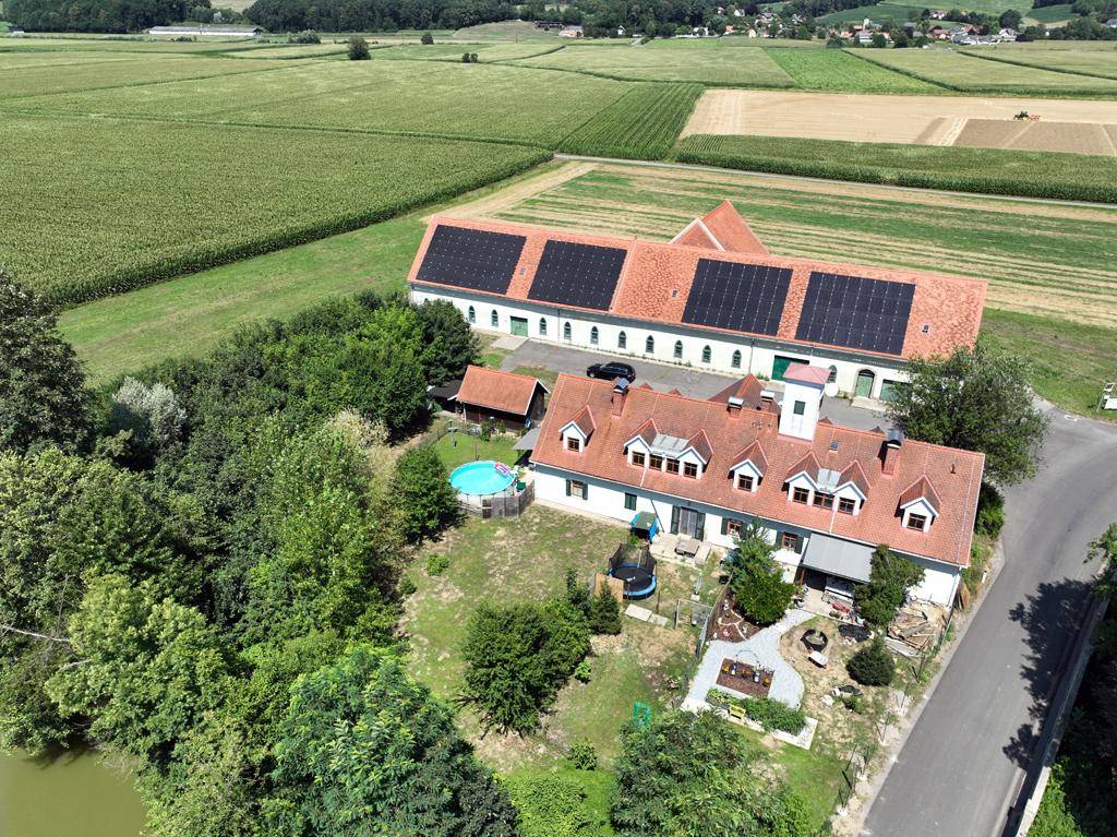 Luftaufnahme des gesamten Anwesens mit Wohnhaus, Nebengebäuden, Pool und Photovoltaikanlage.