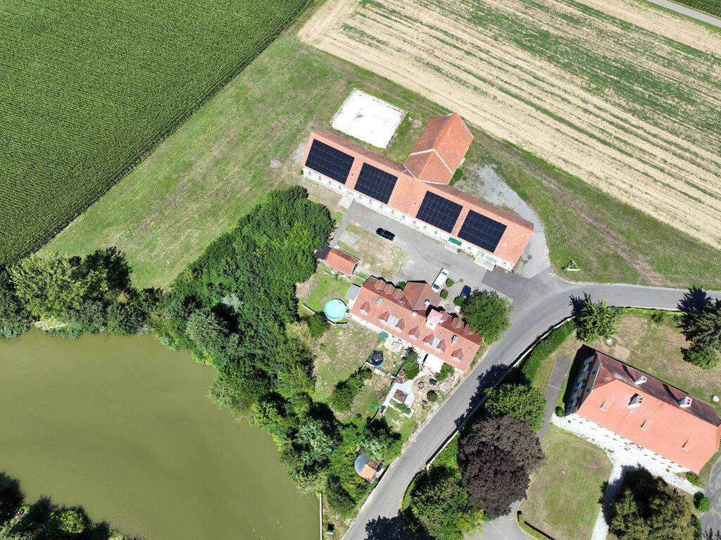 Luftaufnahme des Anwesens mit mehreren Gebäuden, Feldern und einem Teich.