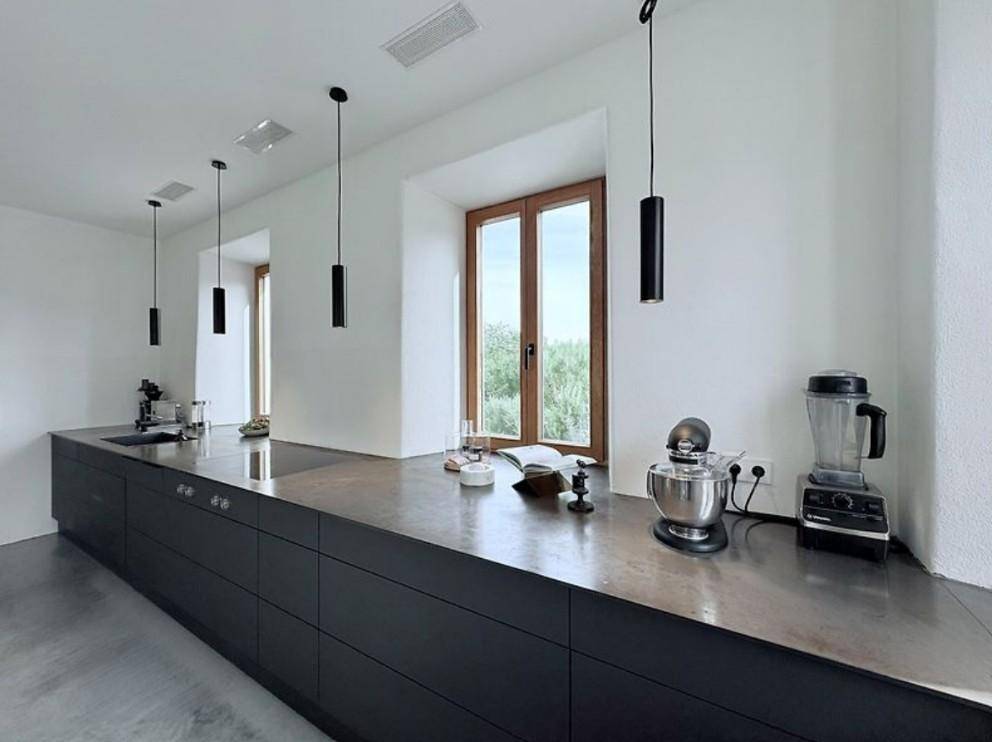 Moderne Küche mit dunklen Schränken, langen Arbeitsplatten und großen Fenstern.