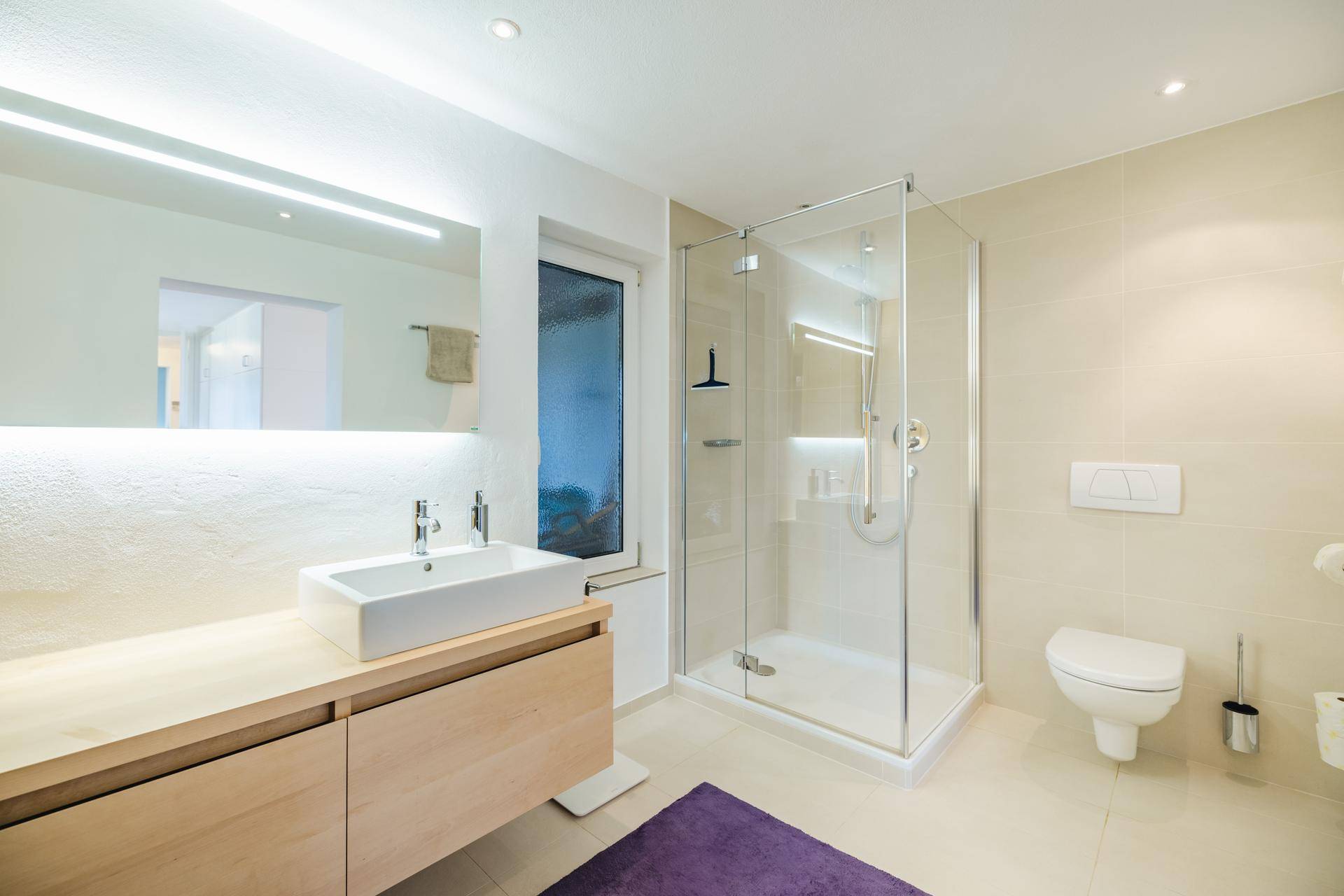 Helles Badezimmer mit begehbarer Dusche, modernem Waschtisch und Wand-WC.