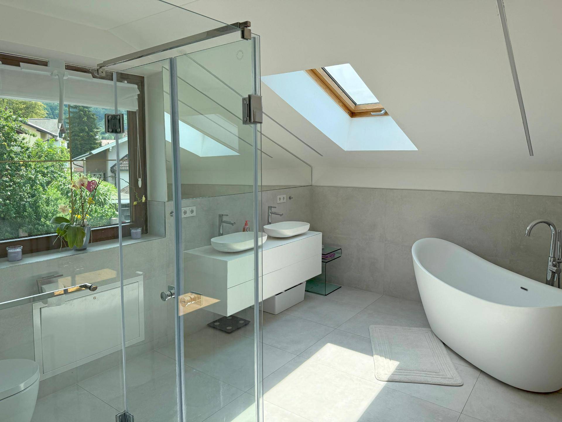 Helles, modernes Badezimmer mit freistehender Badewanne, Doppelwaschbecken und Dachfenster.