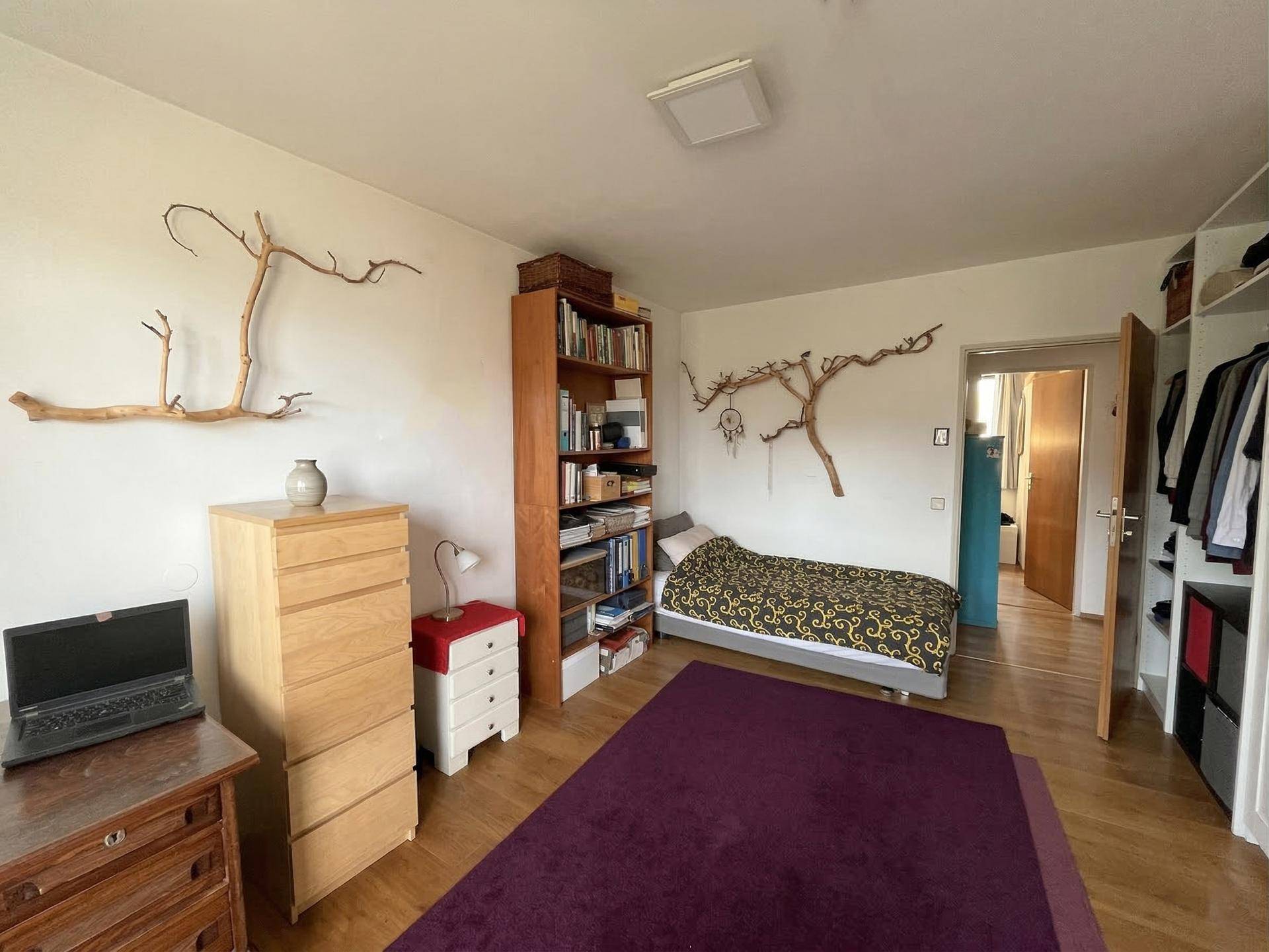 Schlafzimmer mit Einzelbett, Kommode, Bücherregal und offenem Kleiderschrank, individuell gestaltet.