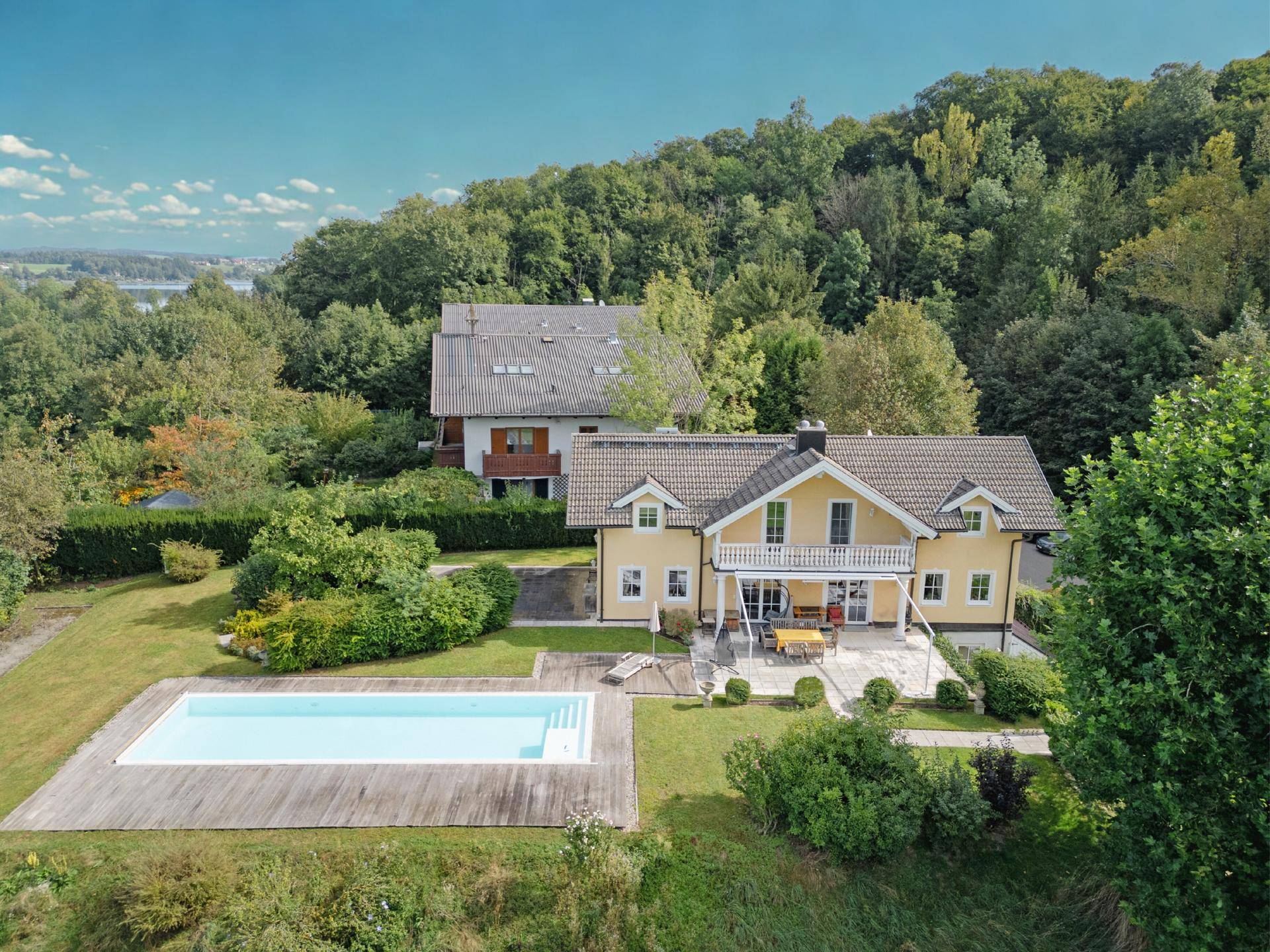 Panoramablick auf das Landhaus mit Pool, Terrasse und weitem Blick auf die Landschaft und einen See.