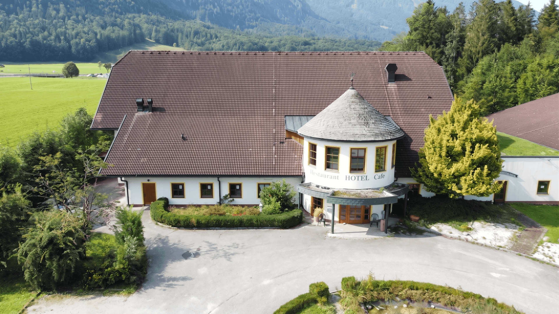 Großes Hotelgebäude mit markantem Rundbau, umgeben von gepflegten Grünflächen und einer Zufahrt.