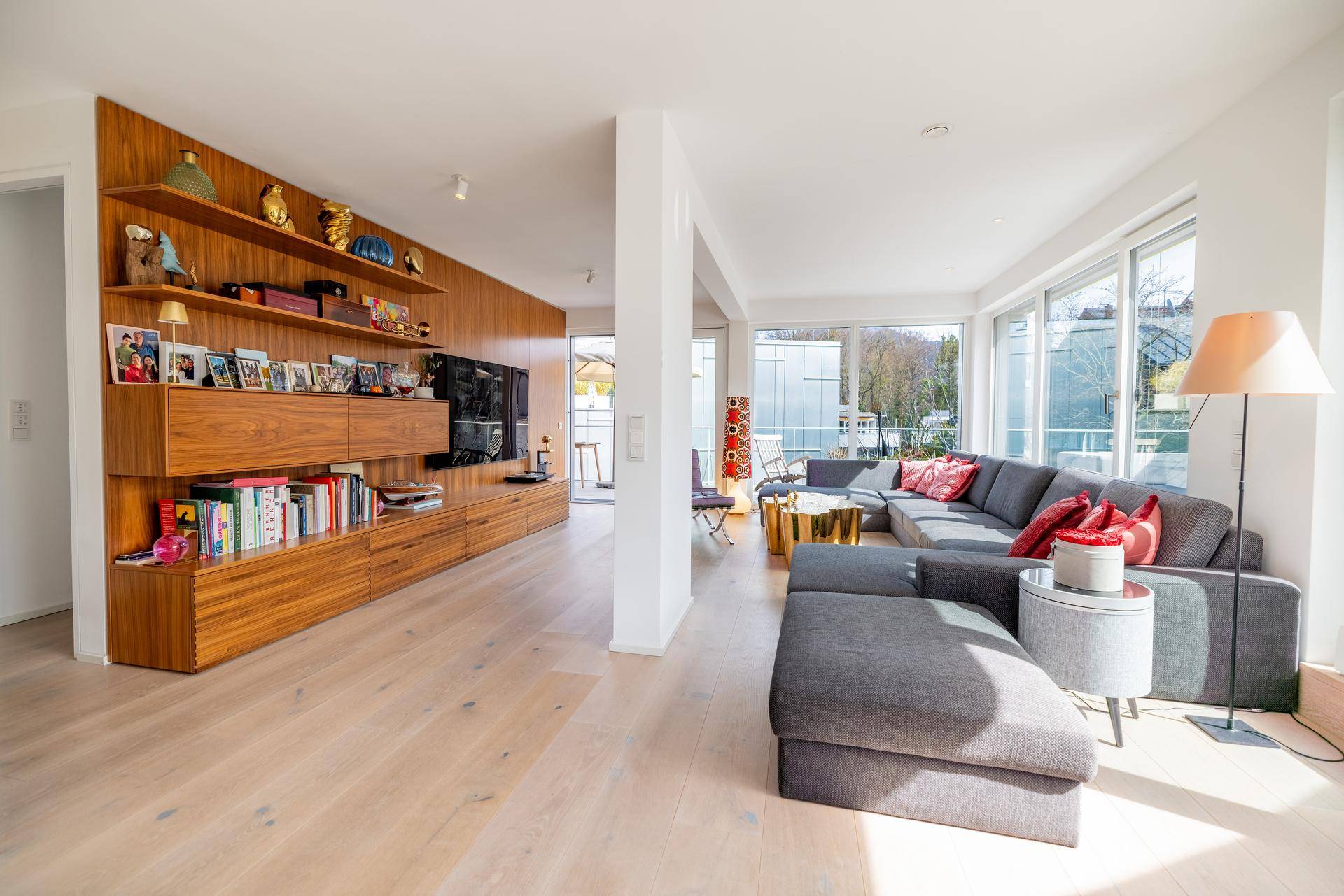 Geräumiges Wohnzimmer mit großem Ecksofa, Holzwandregal und viel Tageslicht.