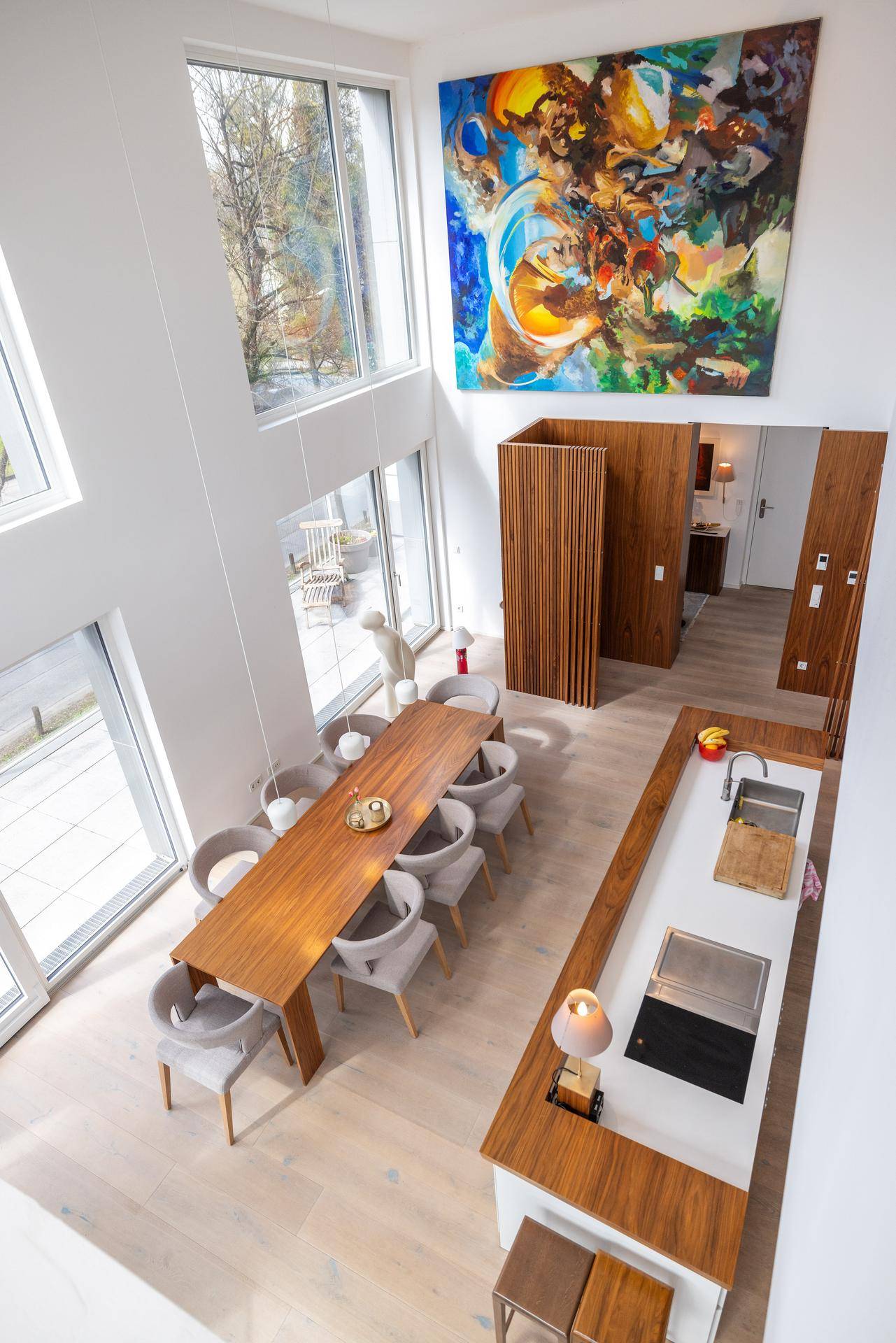Heller, offener Wohn- und Essbereich mit hohen Decken und moderner Kunst an der Wand.