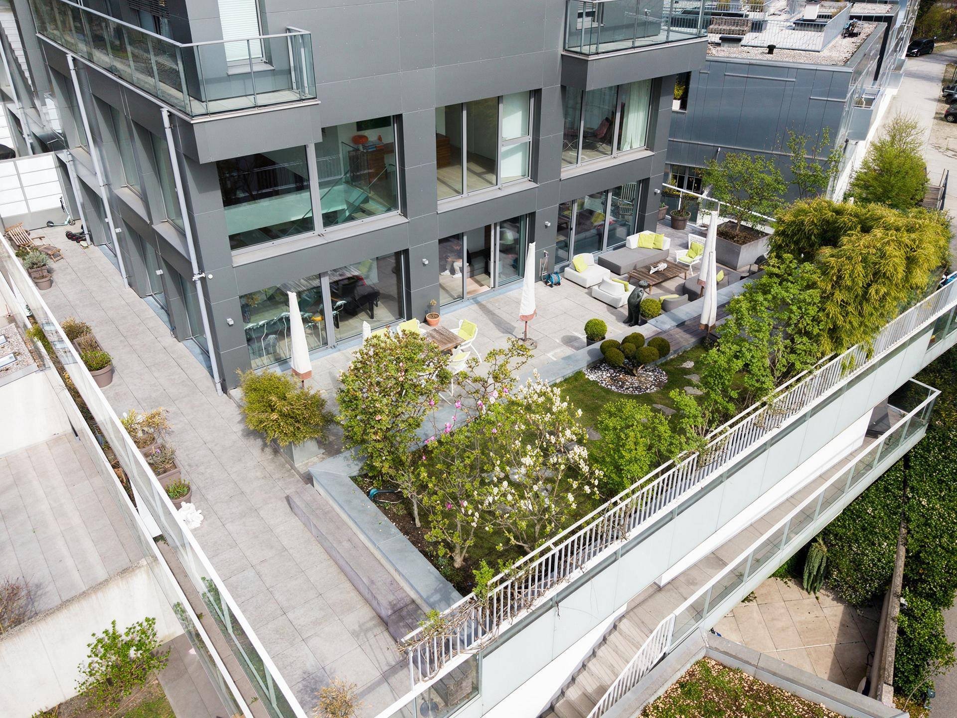 Dachgartenanlage mit üppiger Bepflanzung, Terrassenbereichen und moderner Architektur.