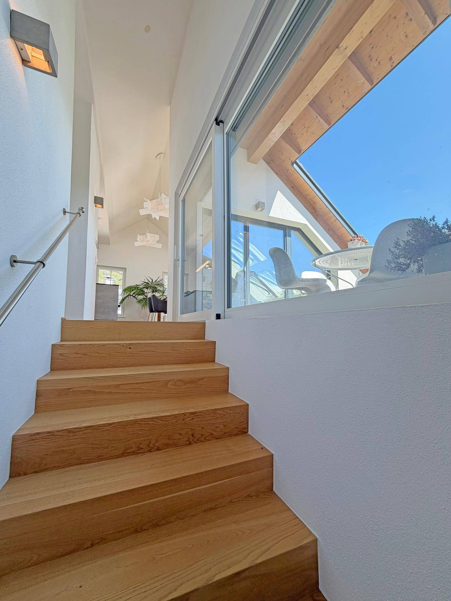 Helle Holztreppe führt in den oberen Wohnbereich mit Blick auf die Terrasse.