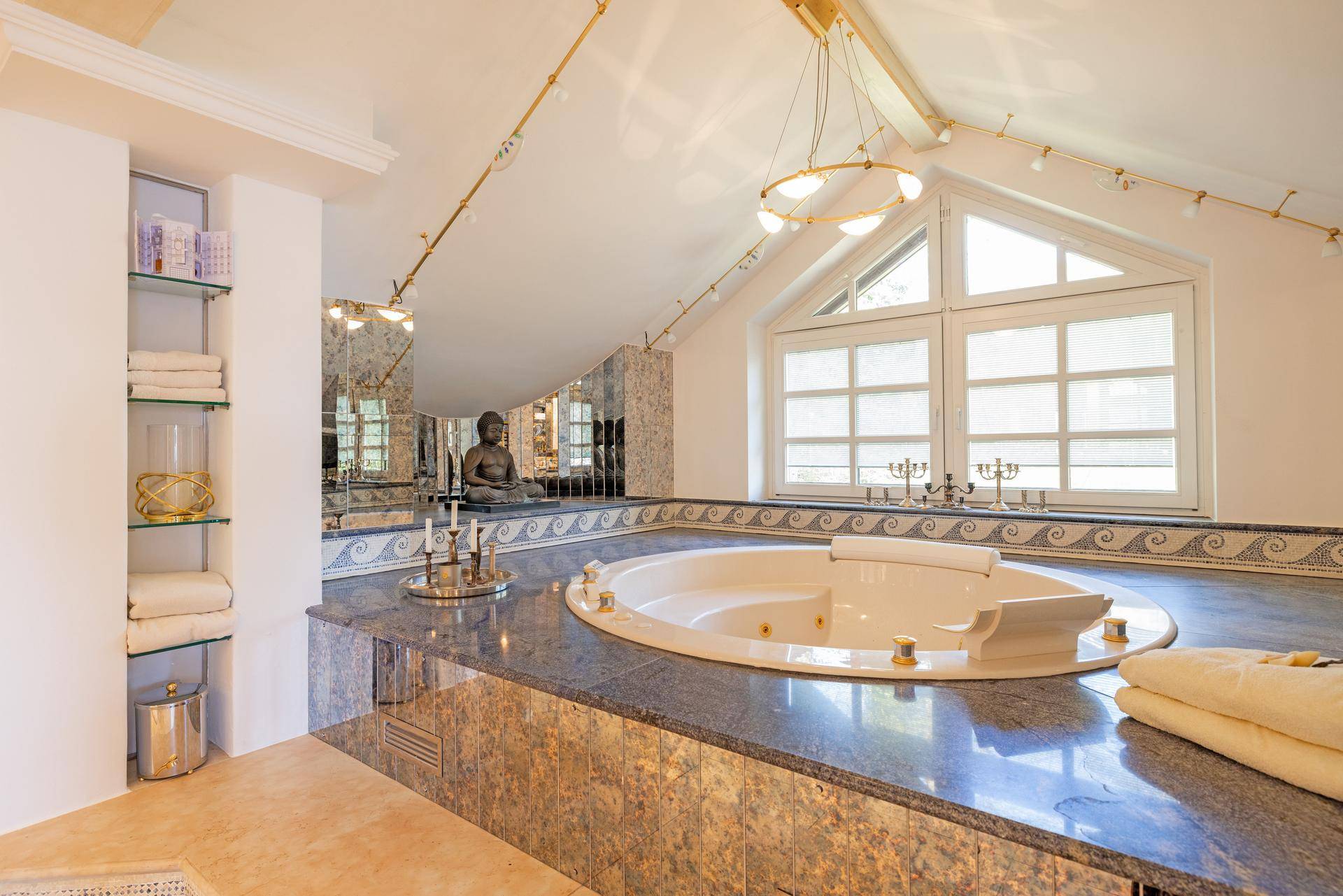 Luxuriöses Badezimmer im Dachgeschoss mit Whirlpool, großen Fenstern und stilvollen Spiegeln.