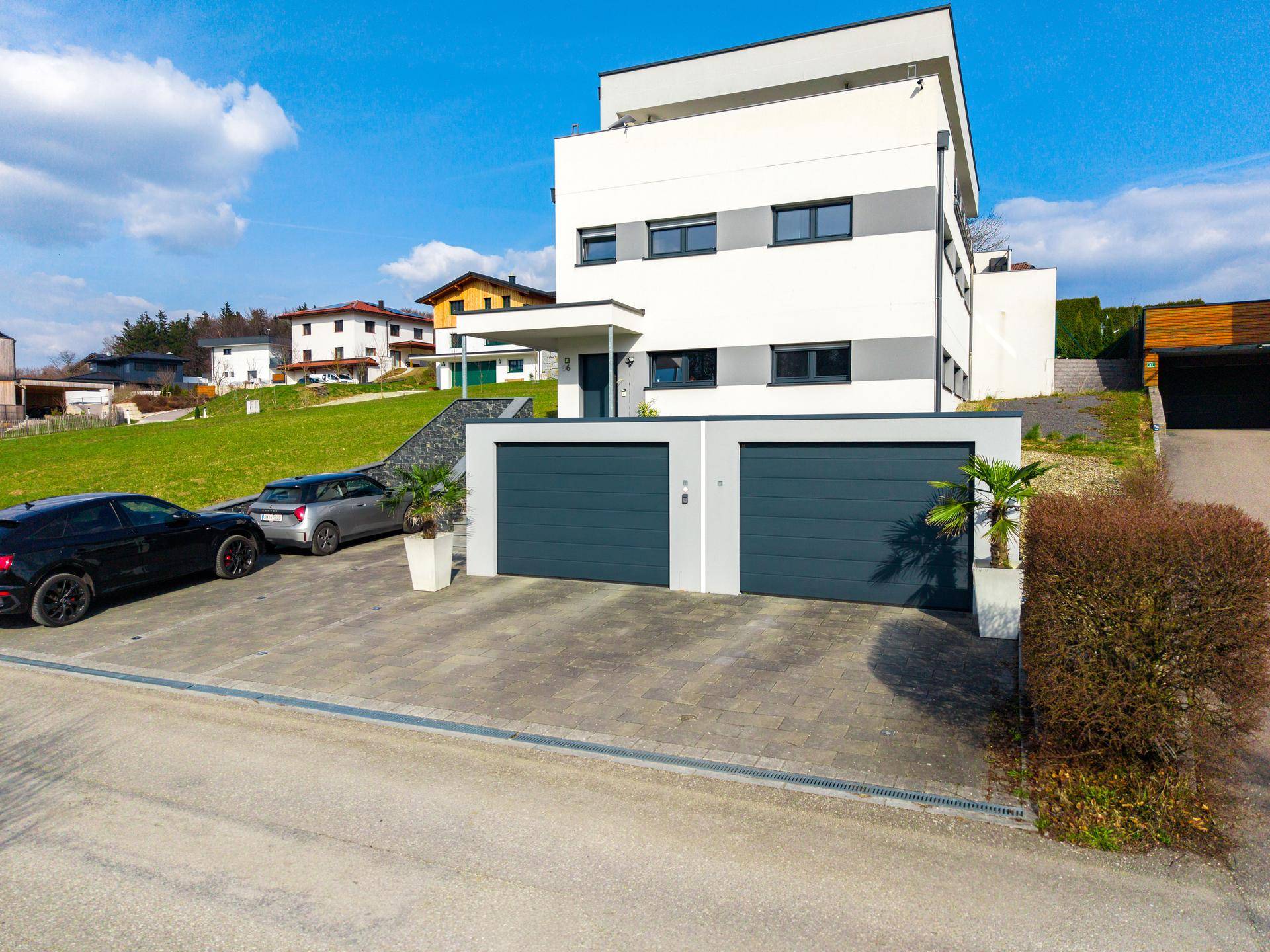 Modernes Wohnhaus mit Doppelgarage, Auffahrt und gepflegter Außenanlage in ländlicher Umgebung.