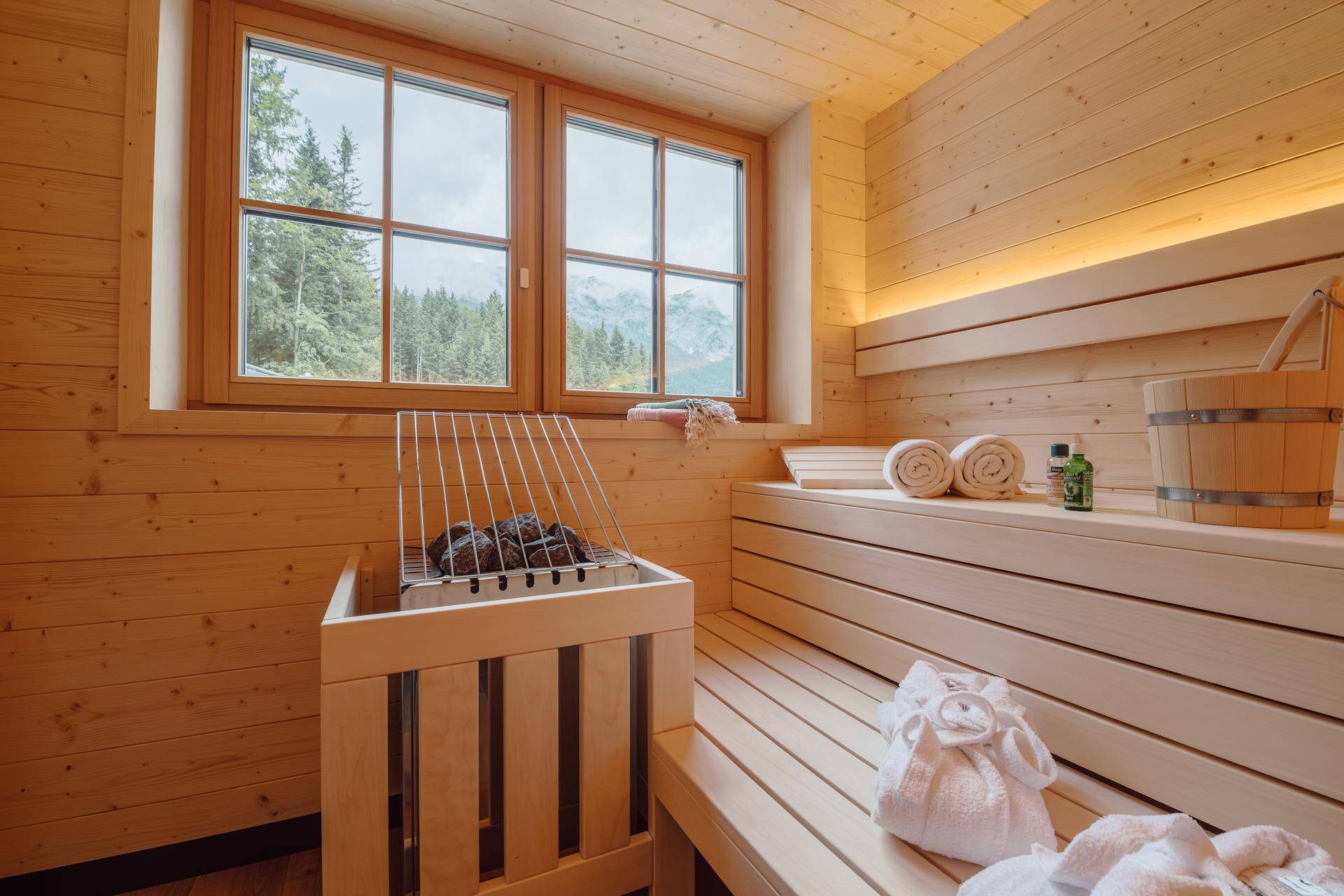 Moderne Holzsauna mit Bänken und Heizofen, bietet einen entspannenden Blick auf die Berge.