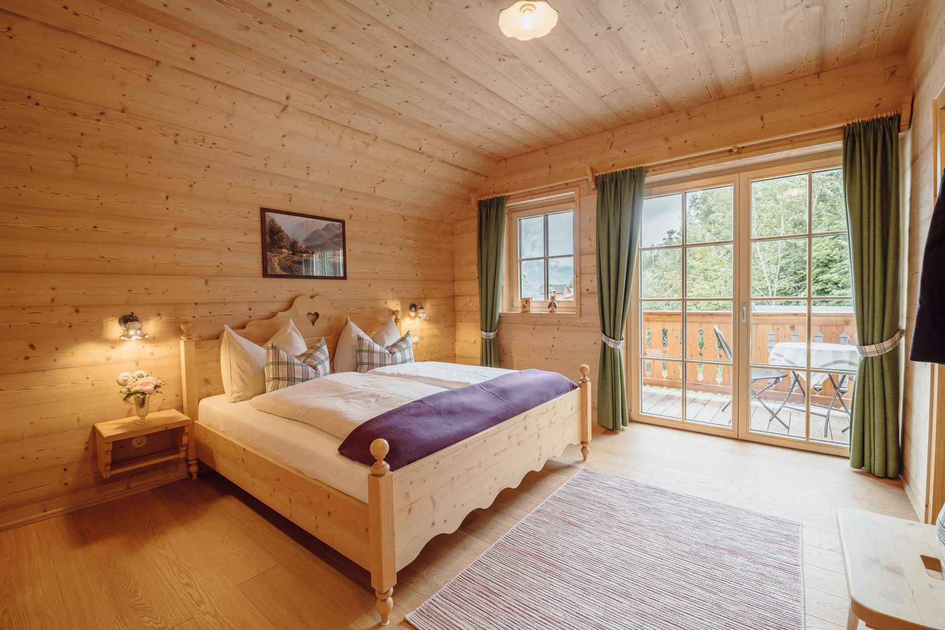 Helles Schlafzimmer mit Holzbett, Holzwänden und direktem Zugang zu einem Balkon mit Bergblick.
