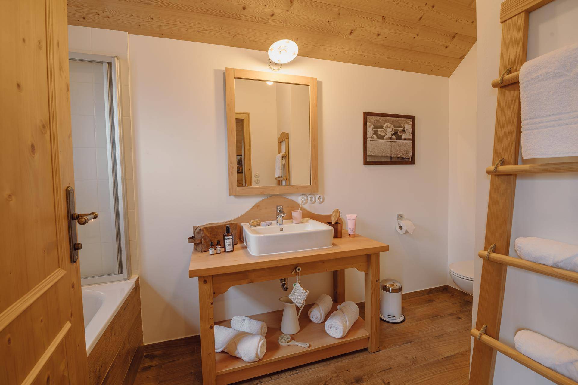 Helles Badezimmer mit Einzelwaschbecken auf Holzunterschrank, Toilette und Duschbereich.