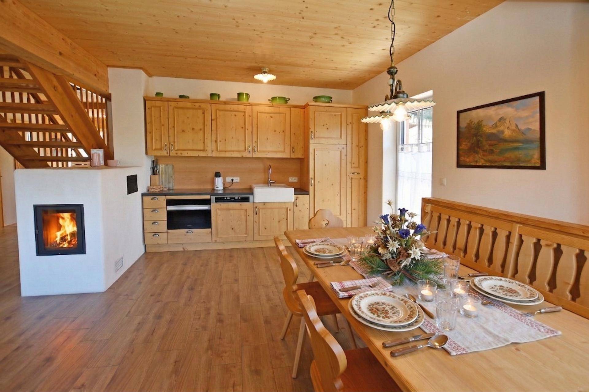 Offene Küche mit Holzeinbauten und Essbereich, ergänzt durch einen modernen Kamin und Holztreppe.