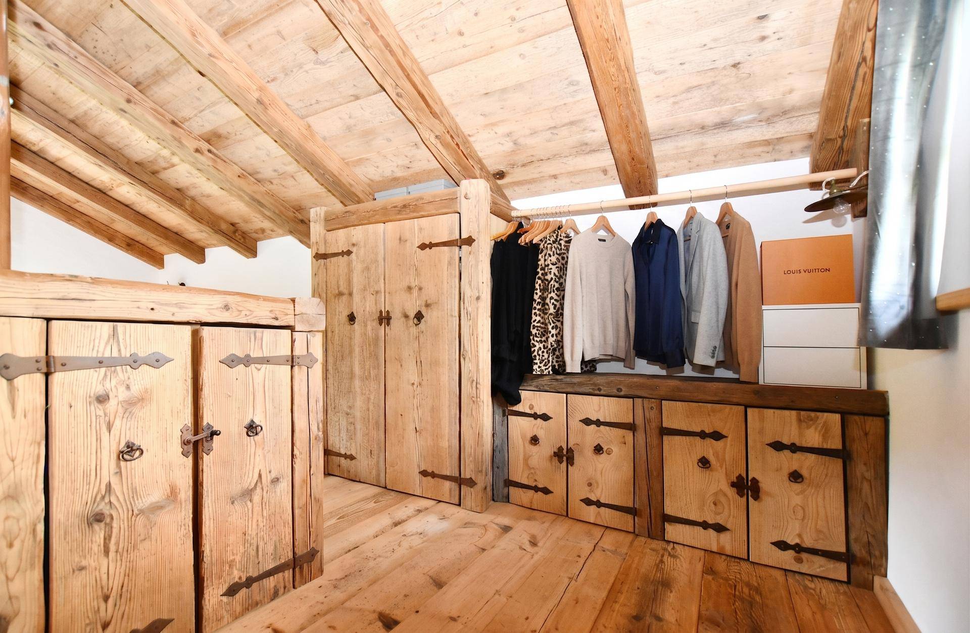 Begehbarer Kleiderschrank mit maßgefertigten Holzschränken und rustikalen Holzbalken.
