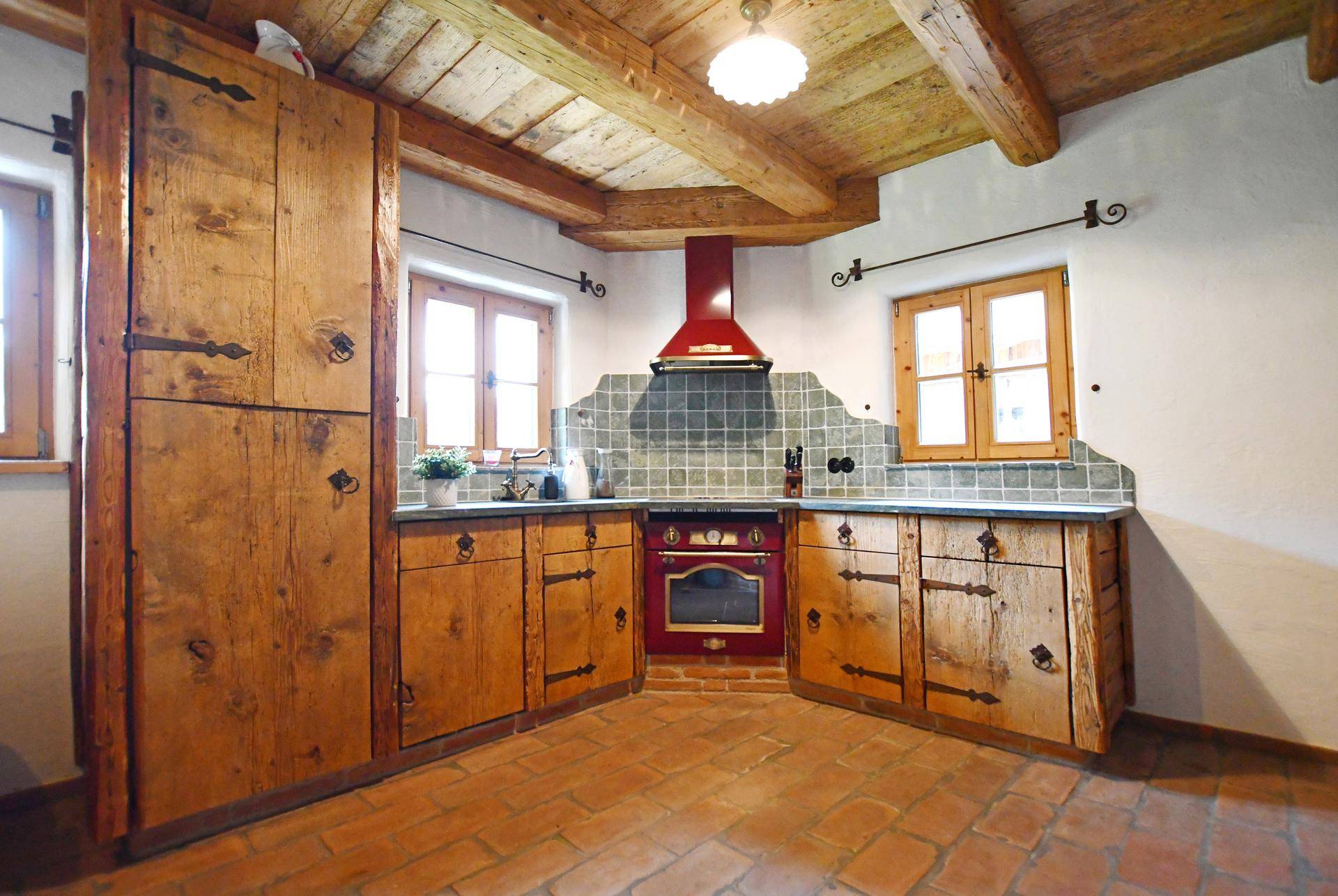 Rustikale Küche mit massiven Holzschränken, Terrakottaboden und freiliegenden Deckenbalken.