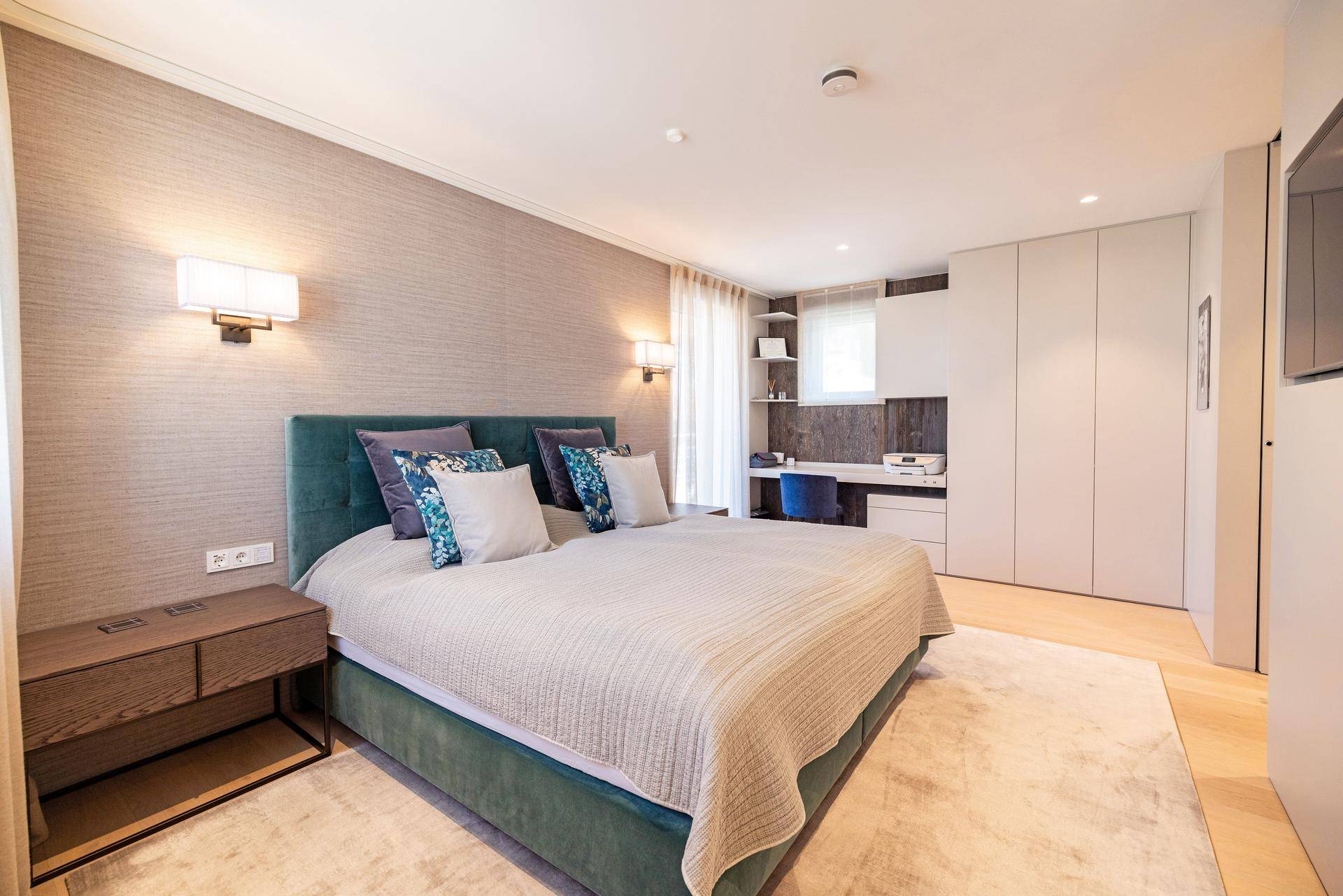 Komfortables Schlafzimmer mit großem Bett, integriertem Arbeitsbereich und Einbauschränken.