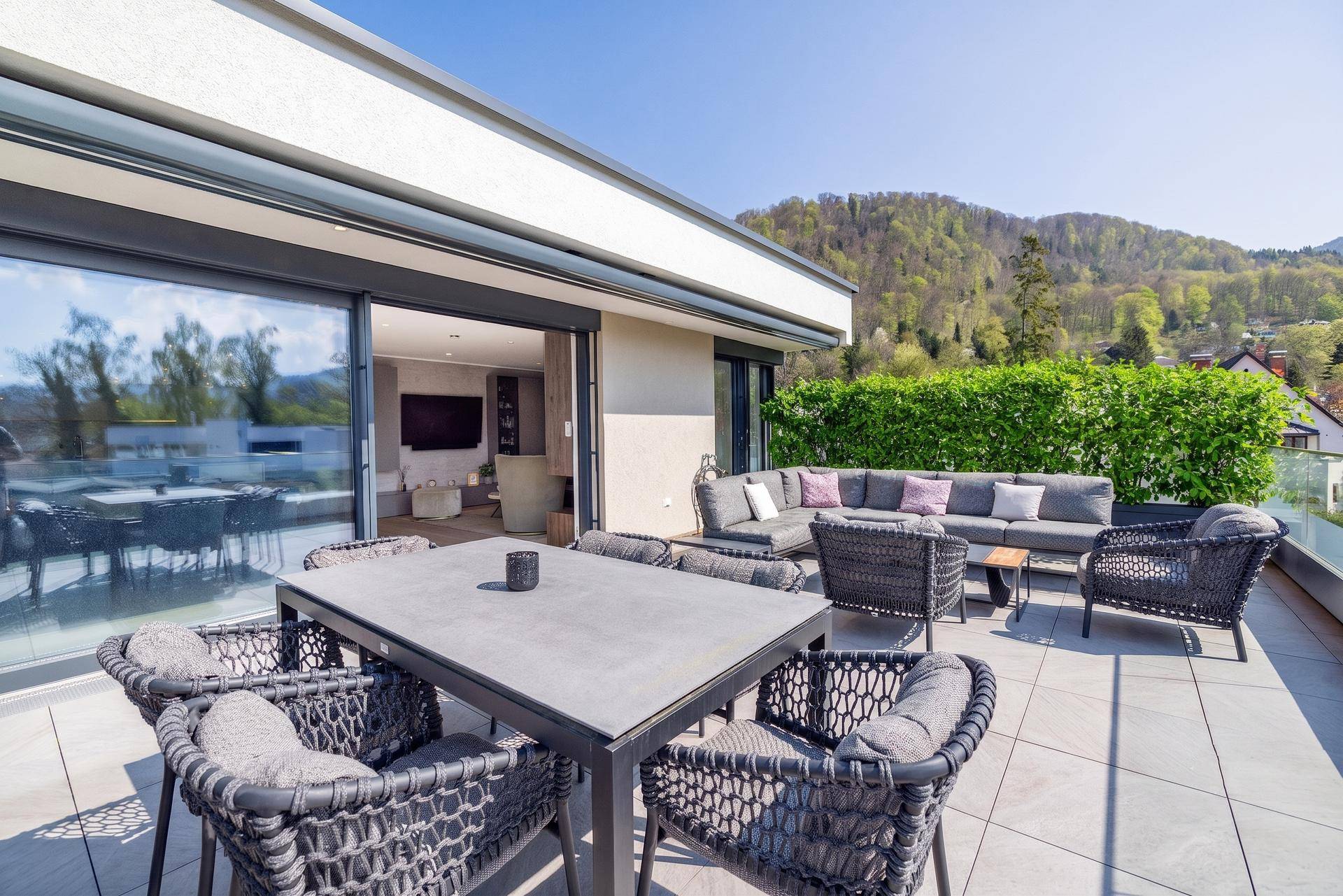 Geräumige Terrasse mit Esstisch und Lounge-Sofa, ideal für Entspannung mit Bergblick.