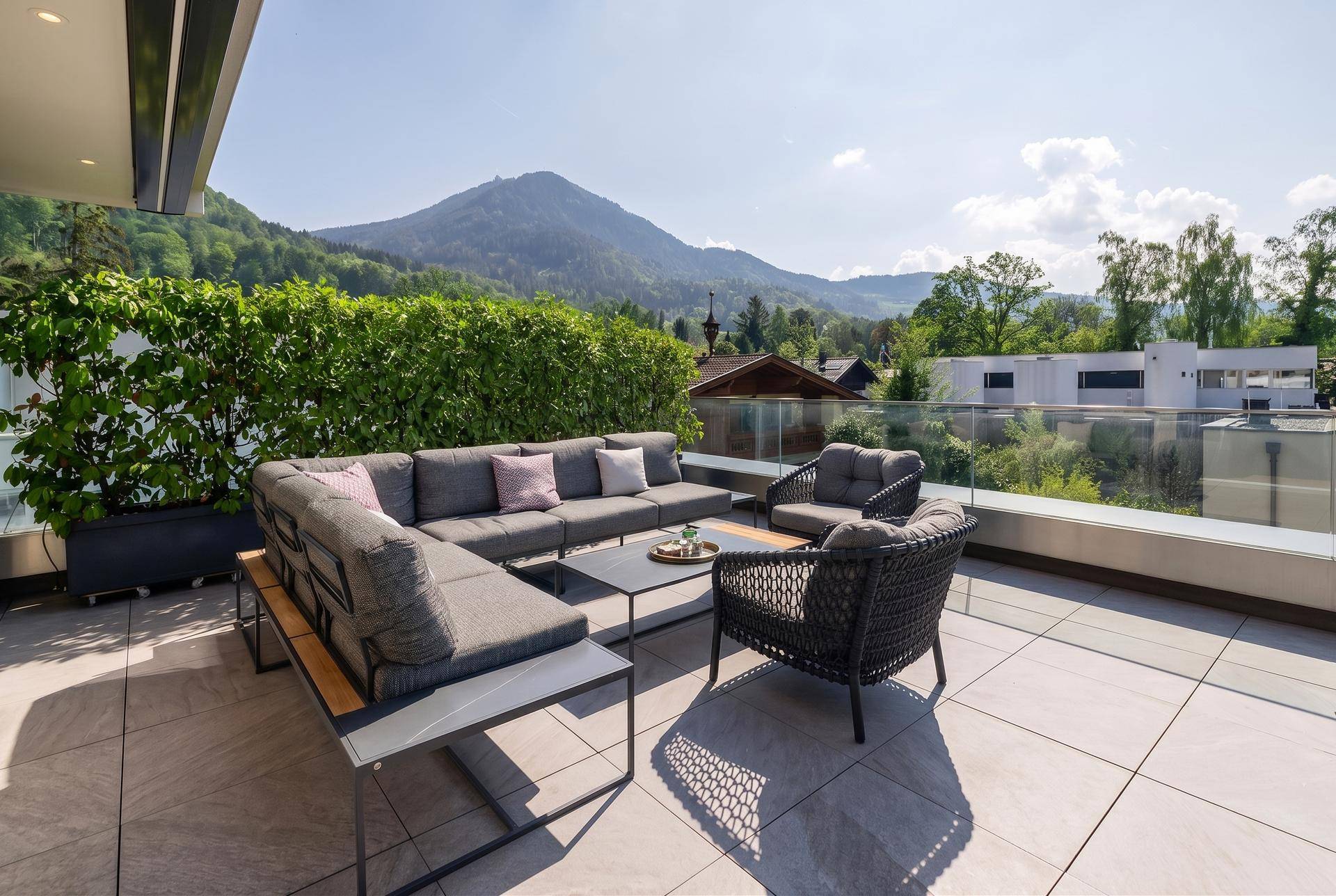 Sonnige Terrasse mit bequemen Lounge-Möbeln und weitem Blick auf die umliegende Berglandschaft.
