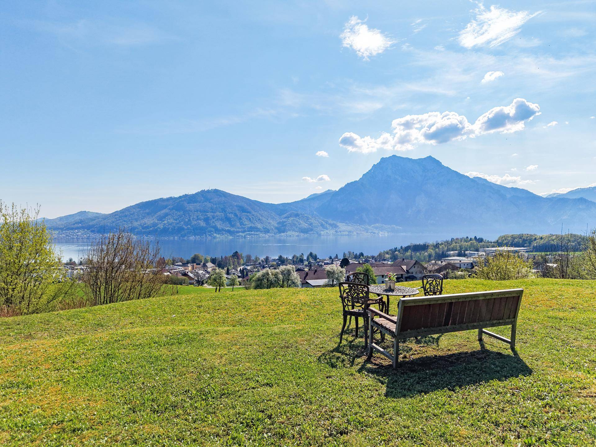 Weitläufiger Gartenbereich mit Sitzgelegenheiten und atemberaubendem Blick auf den See und die Berge.