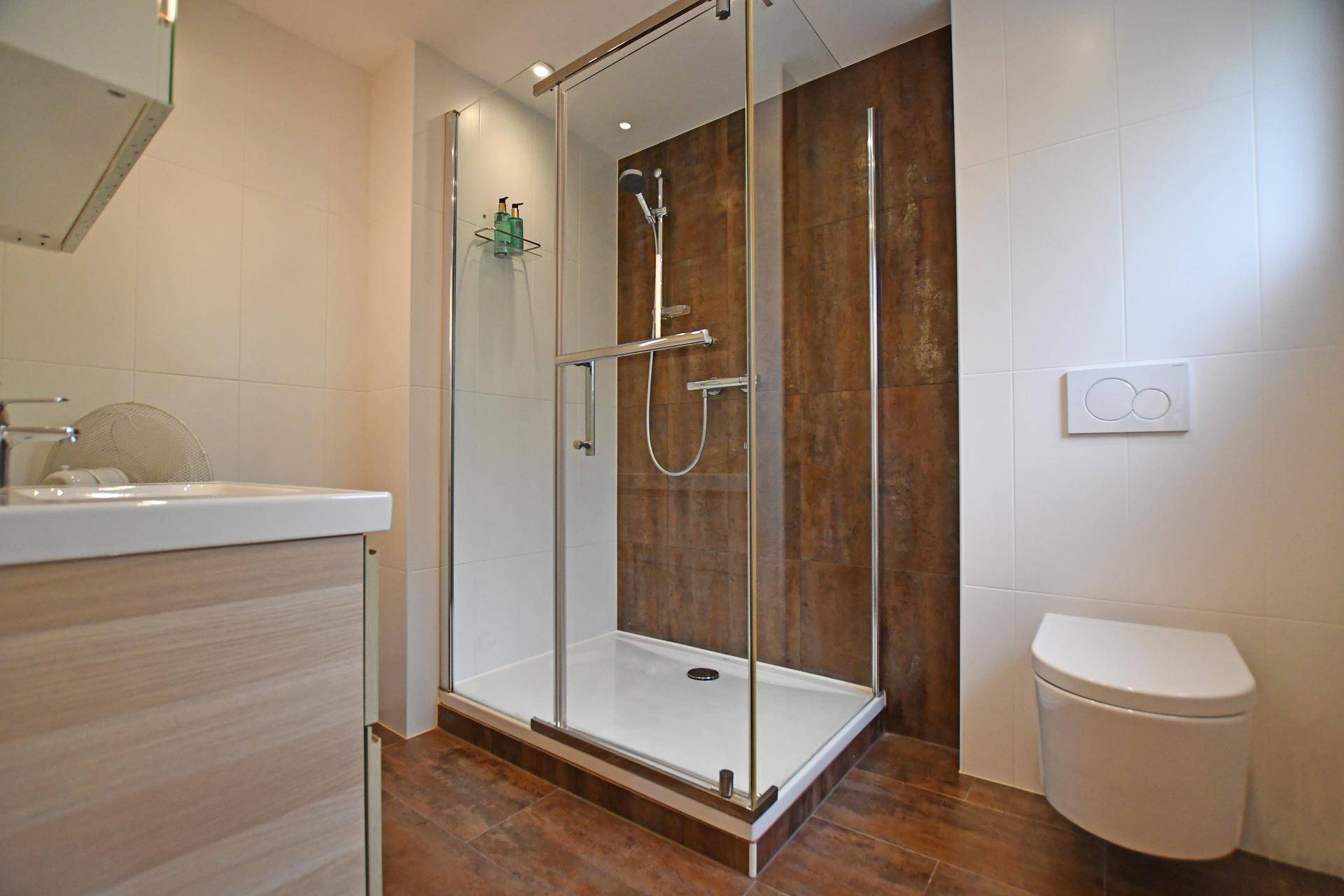 Modernes Badezimmer mit begehbarer Dusche, Wand-WC und stilvollen Fliesen.