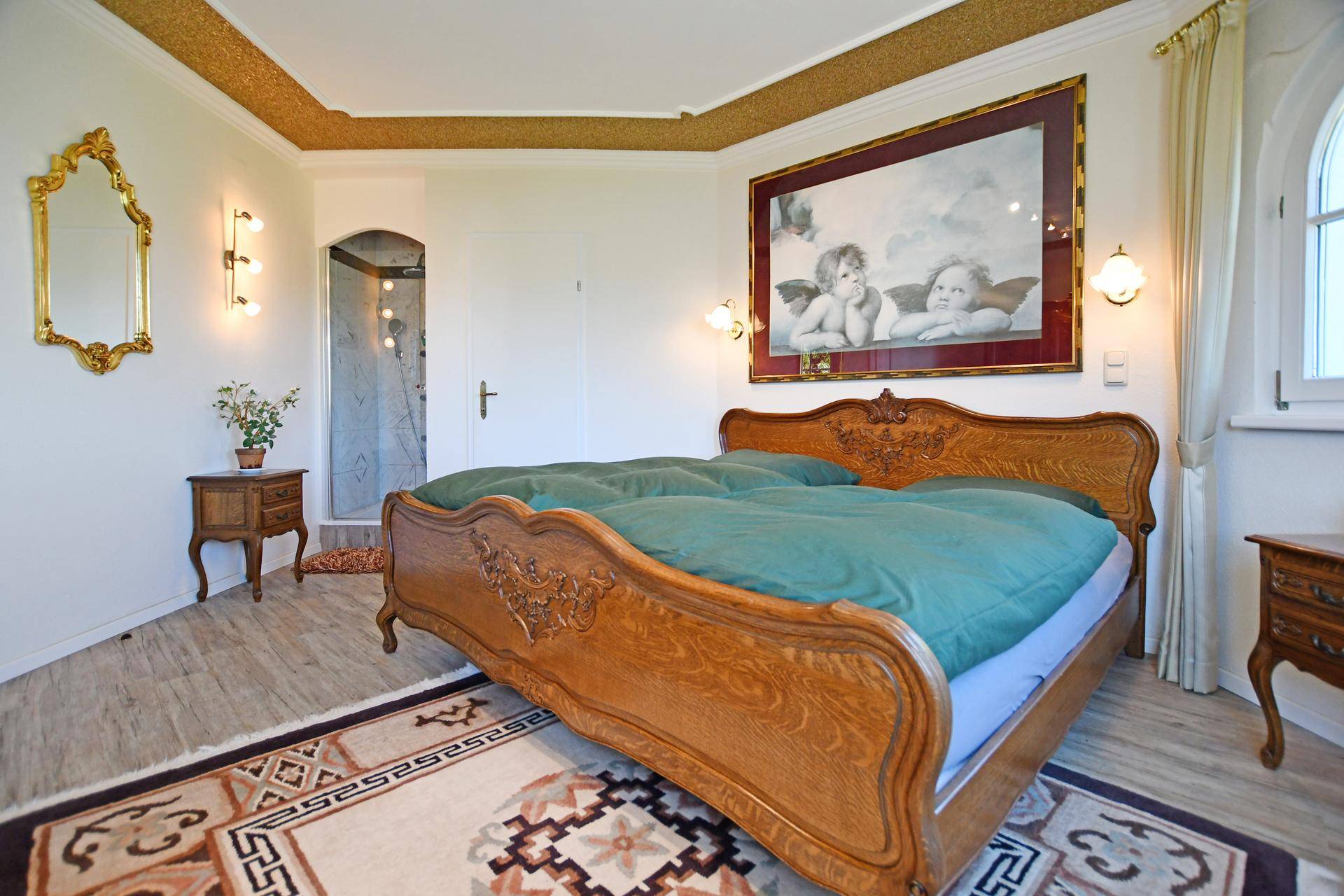 Gemütliches Schlafzimmer mit Holzbett, Teppich und integriertem Duschbereich.