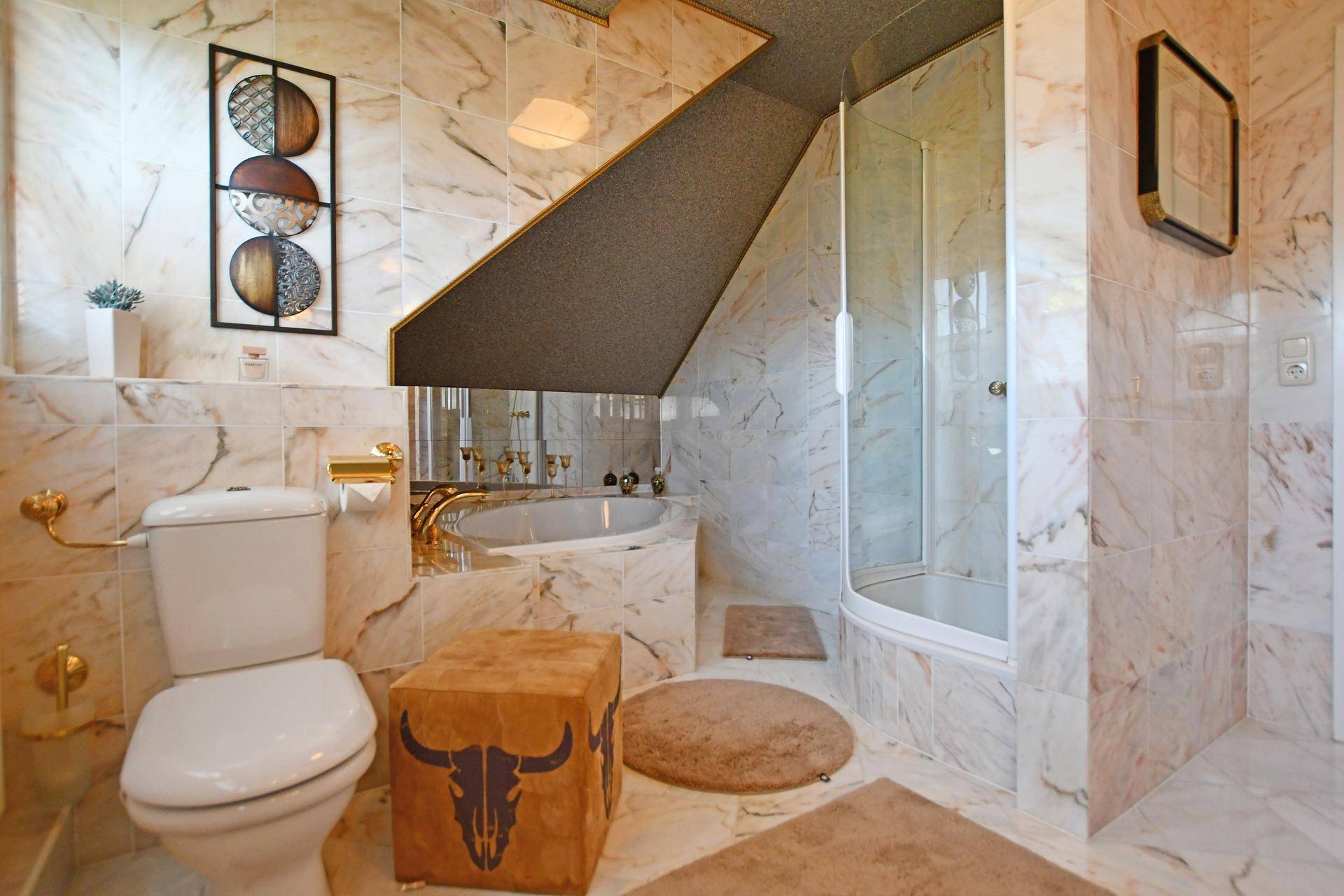 Luxuriöses Badezimmer mit Marmorfliesen, Badewanne, Dusche und Dachschräge.