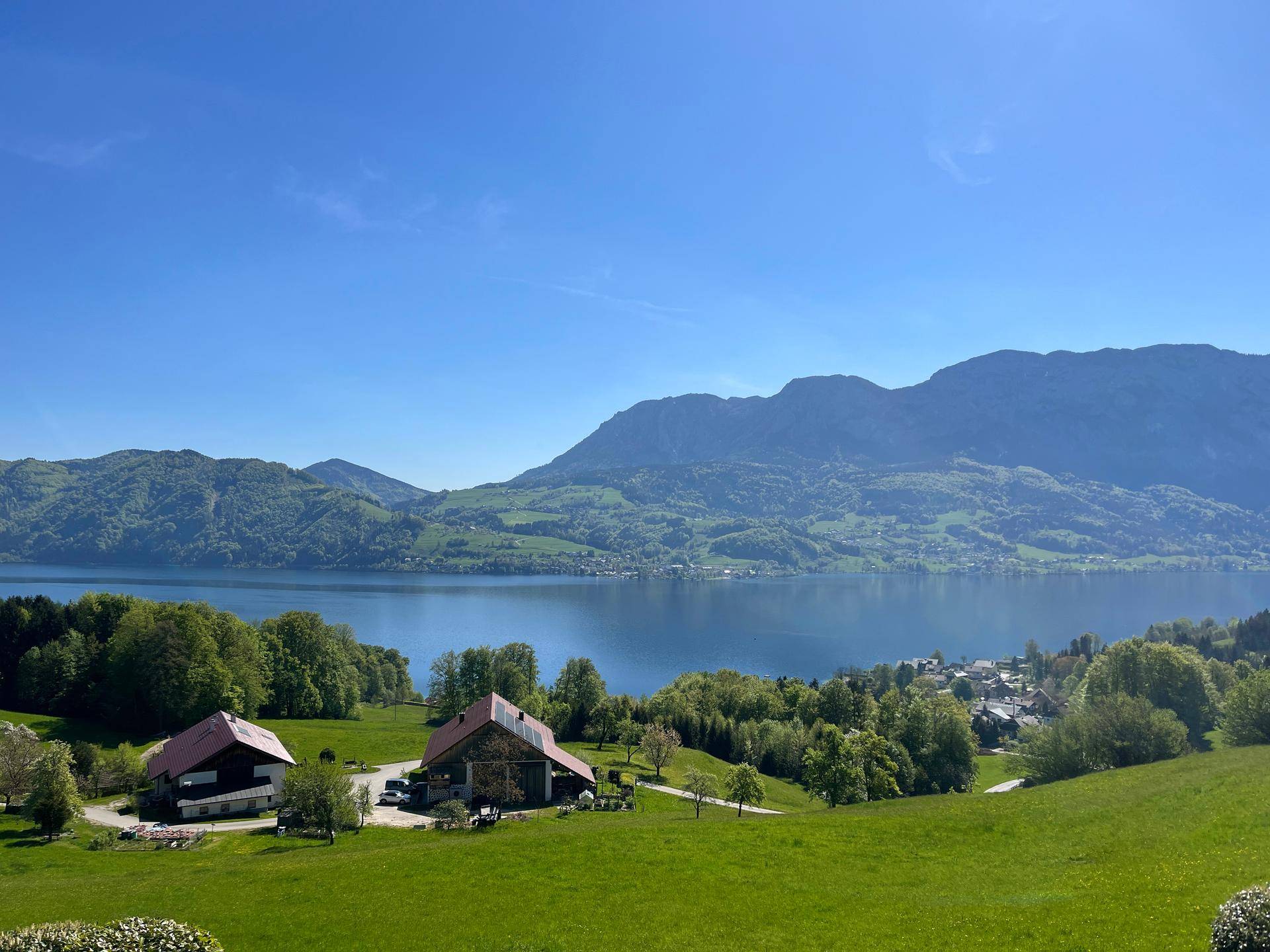 Atemberaubender Blick auf den See und die umliegenden Berge unter blauem Himmel.